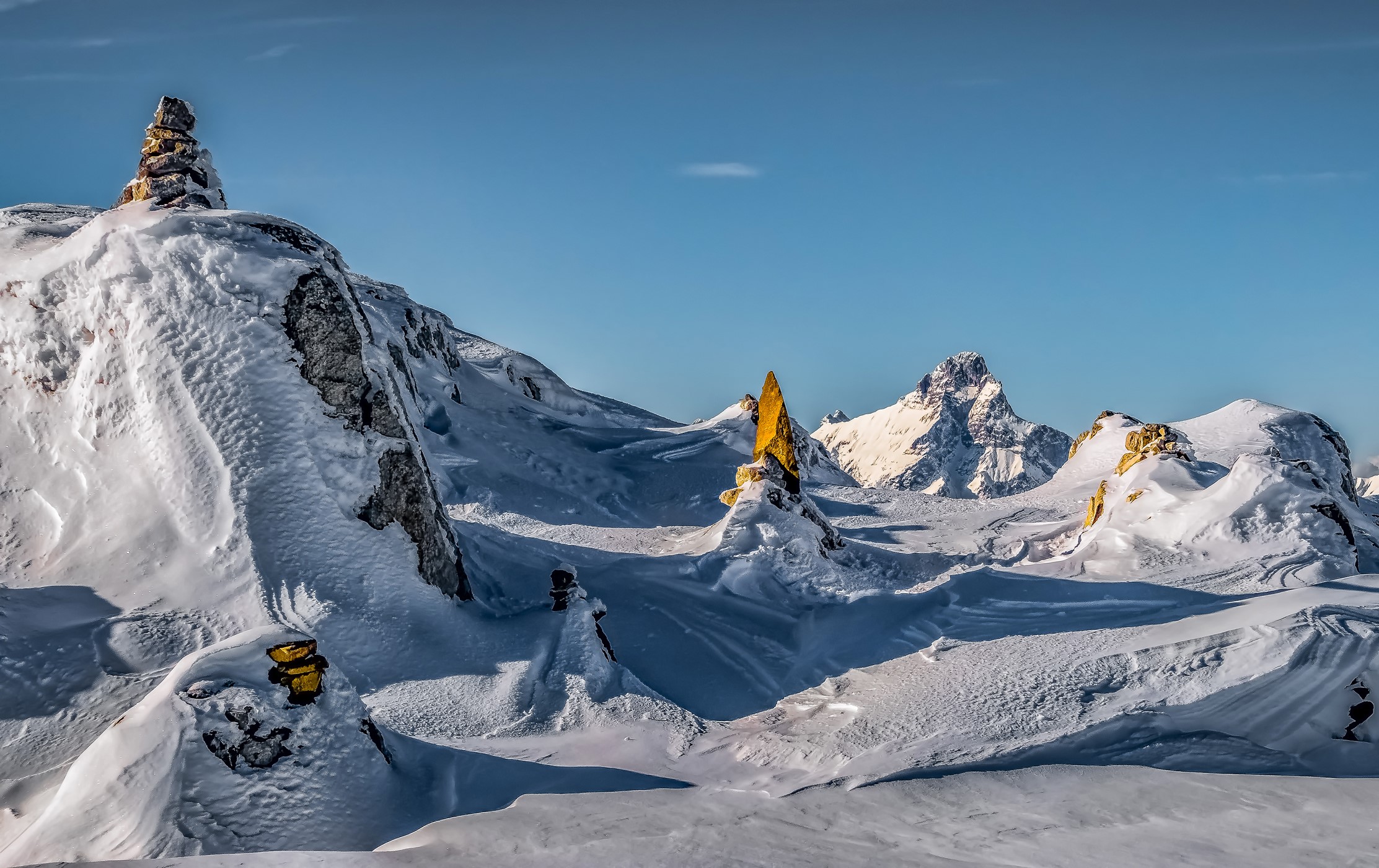 Snowy Alps mountains with rock formations under a clear blue sky HD Wallpaper