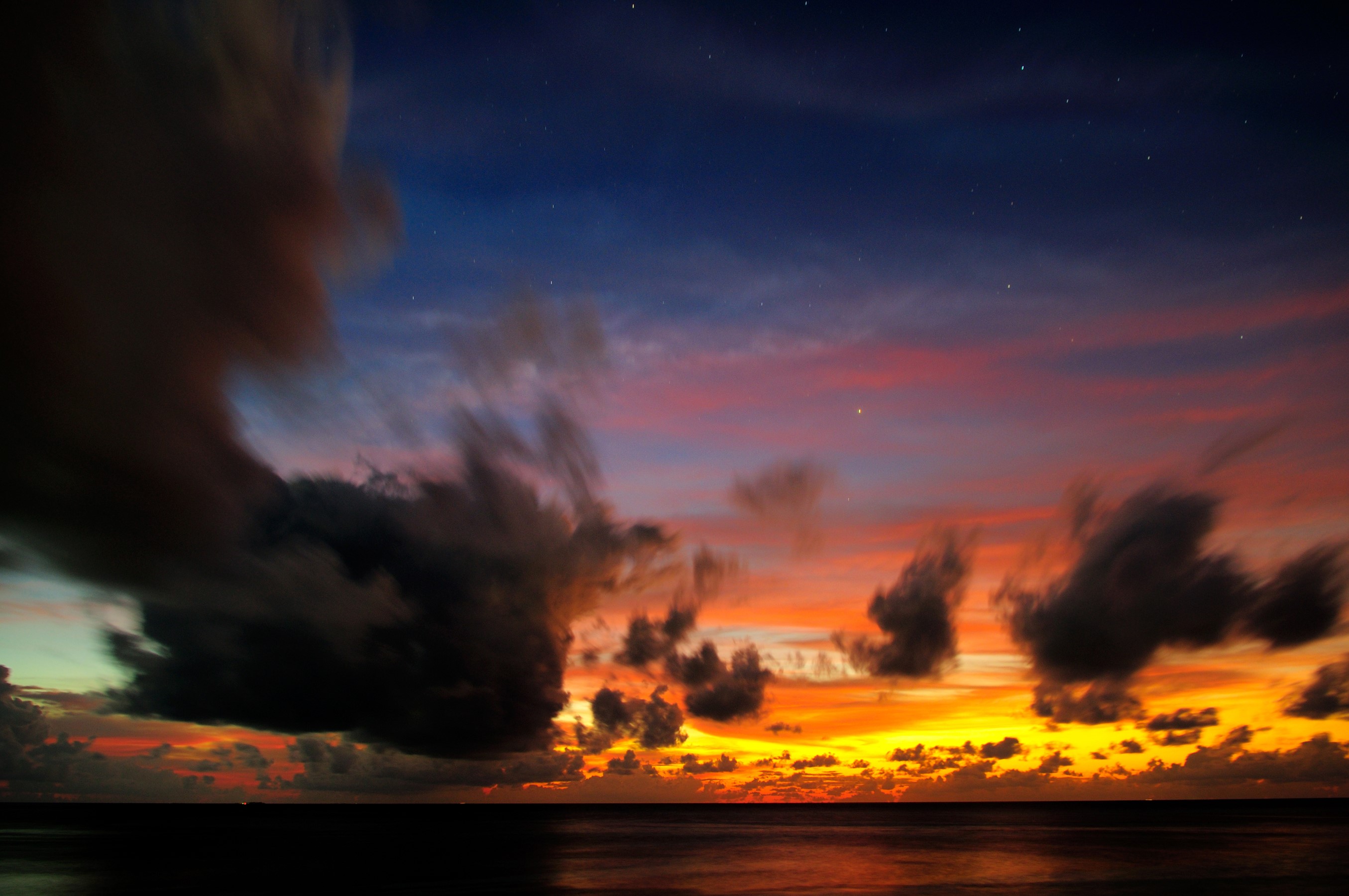 Sunset over the ocean with dramatic clouds and stars HD Wallpaper