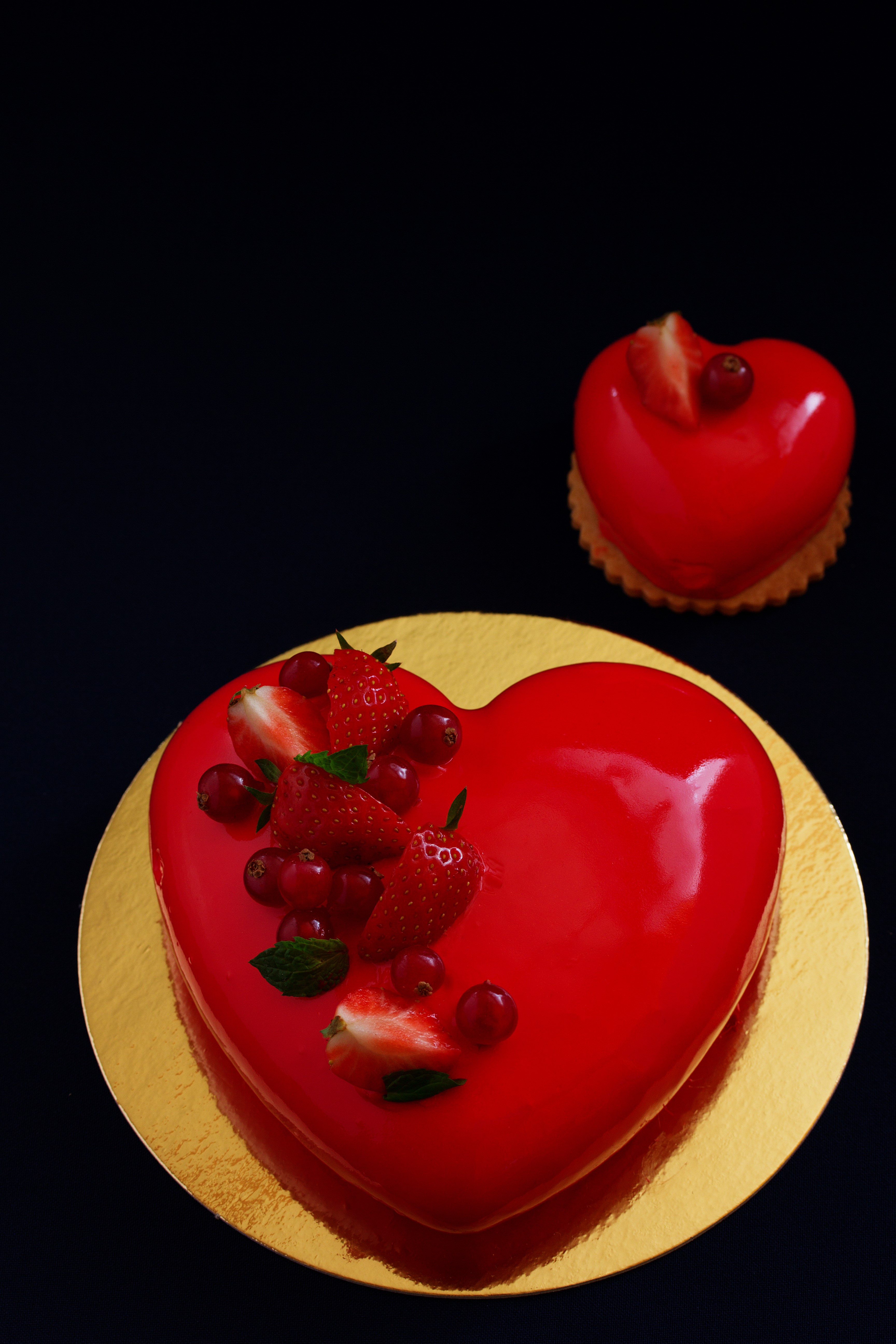 Heart-shaped red mousse cakes with berries on a black background HD Phone Wallpaper