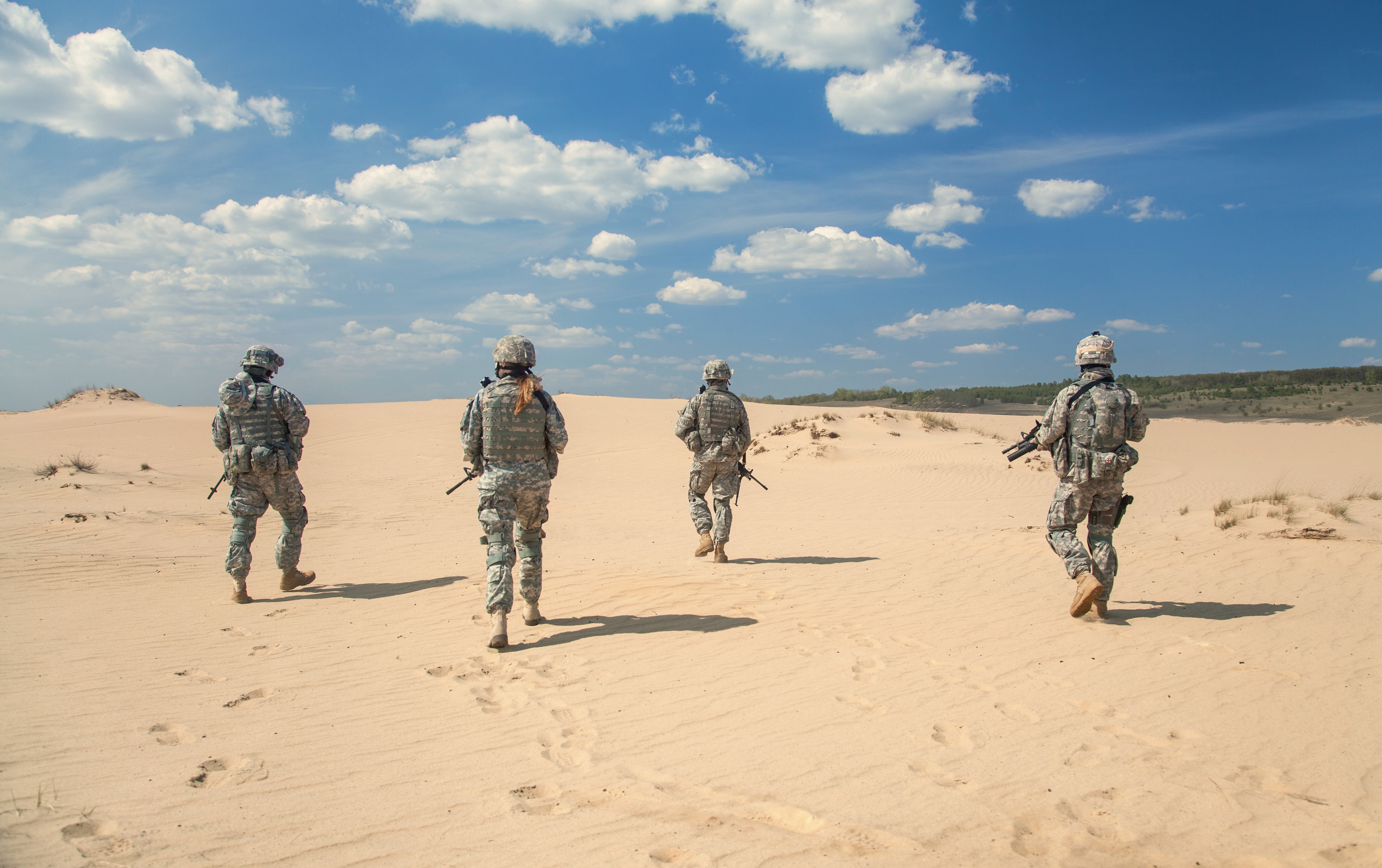 Soldiers in uniform walking in sand dunes HD Wallpaper
