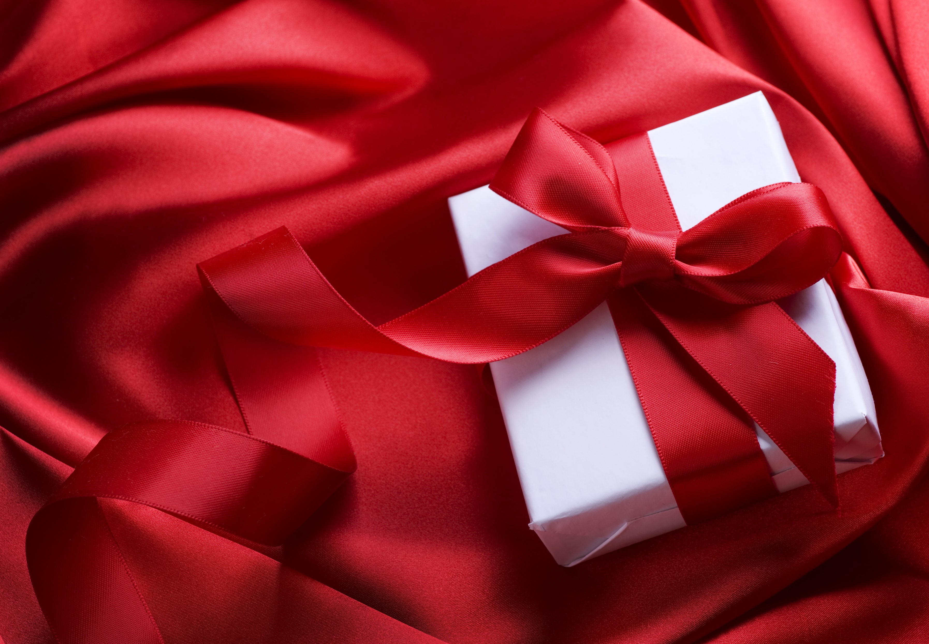 Gift box with red ribbon on red satin HD Wallpaper