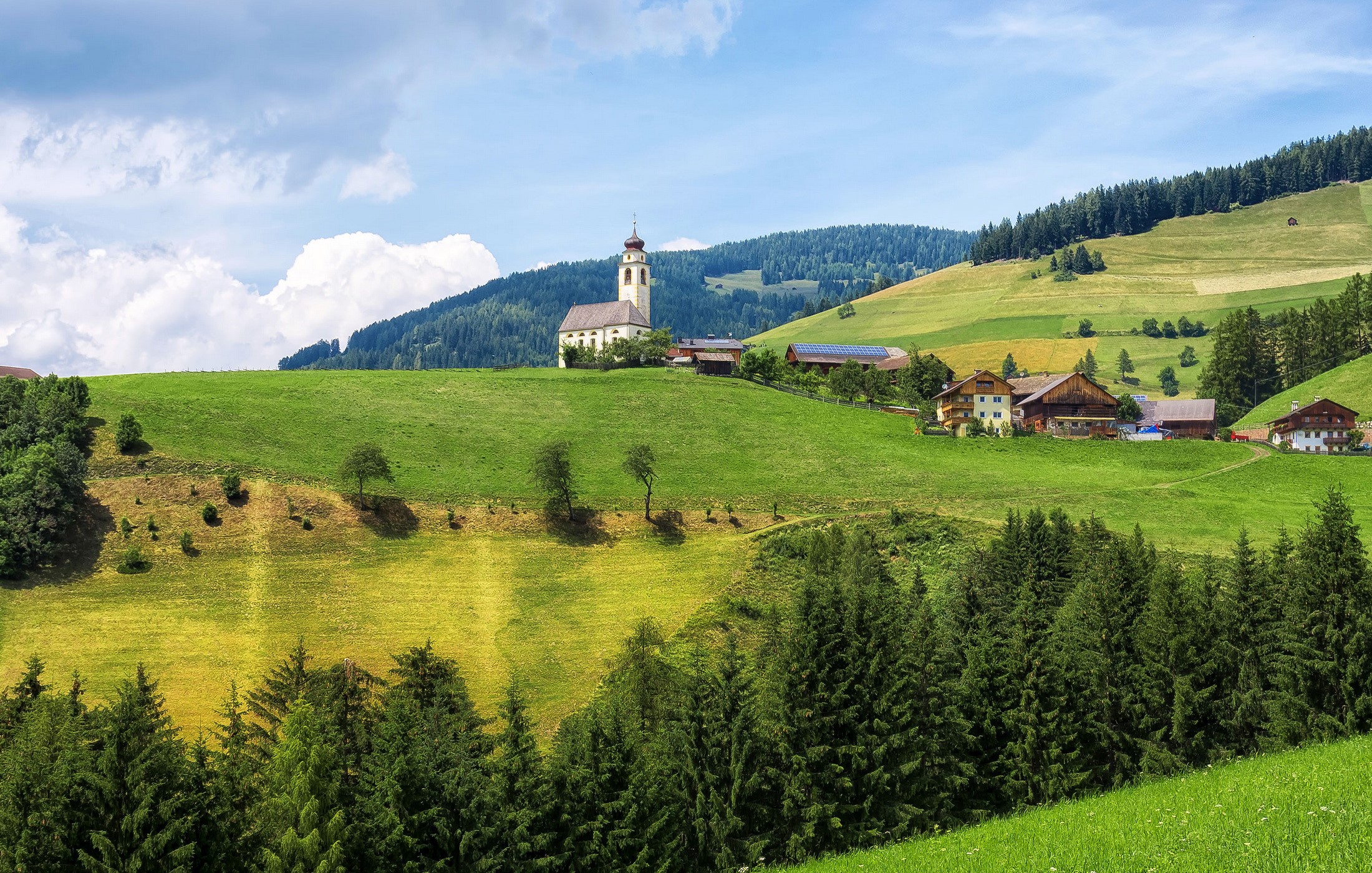 Church and houses on a grassy hill in Marebbe, Italy HD Wallpaper
