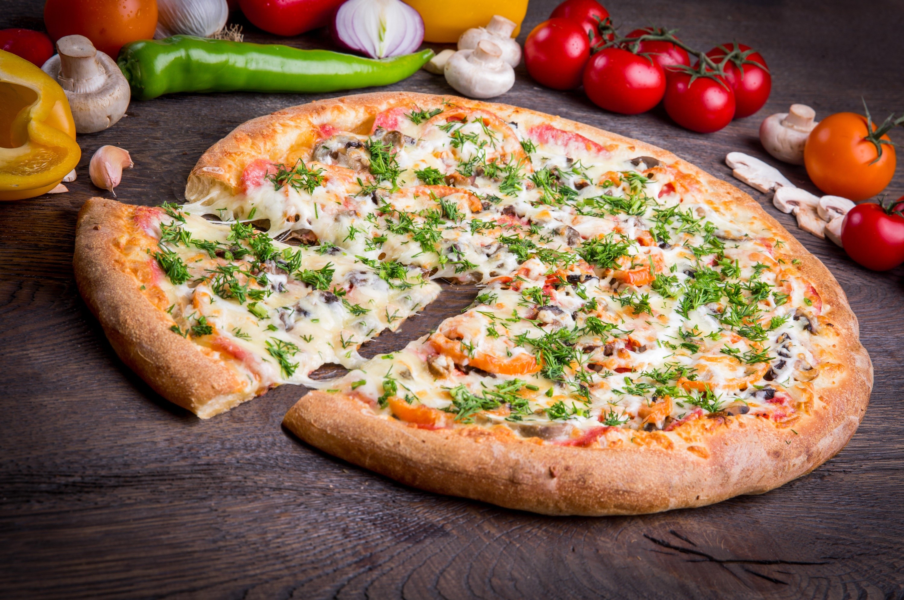 Pizza with cheese and herbs on a wooden table HD Wallpaper