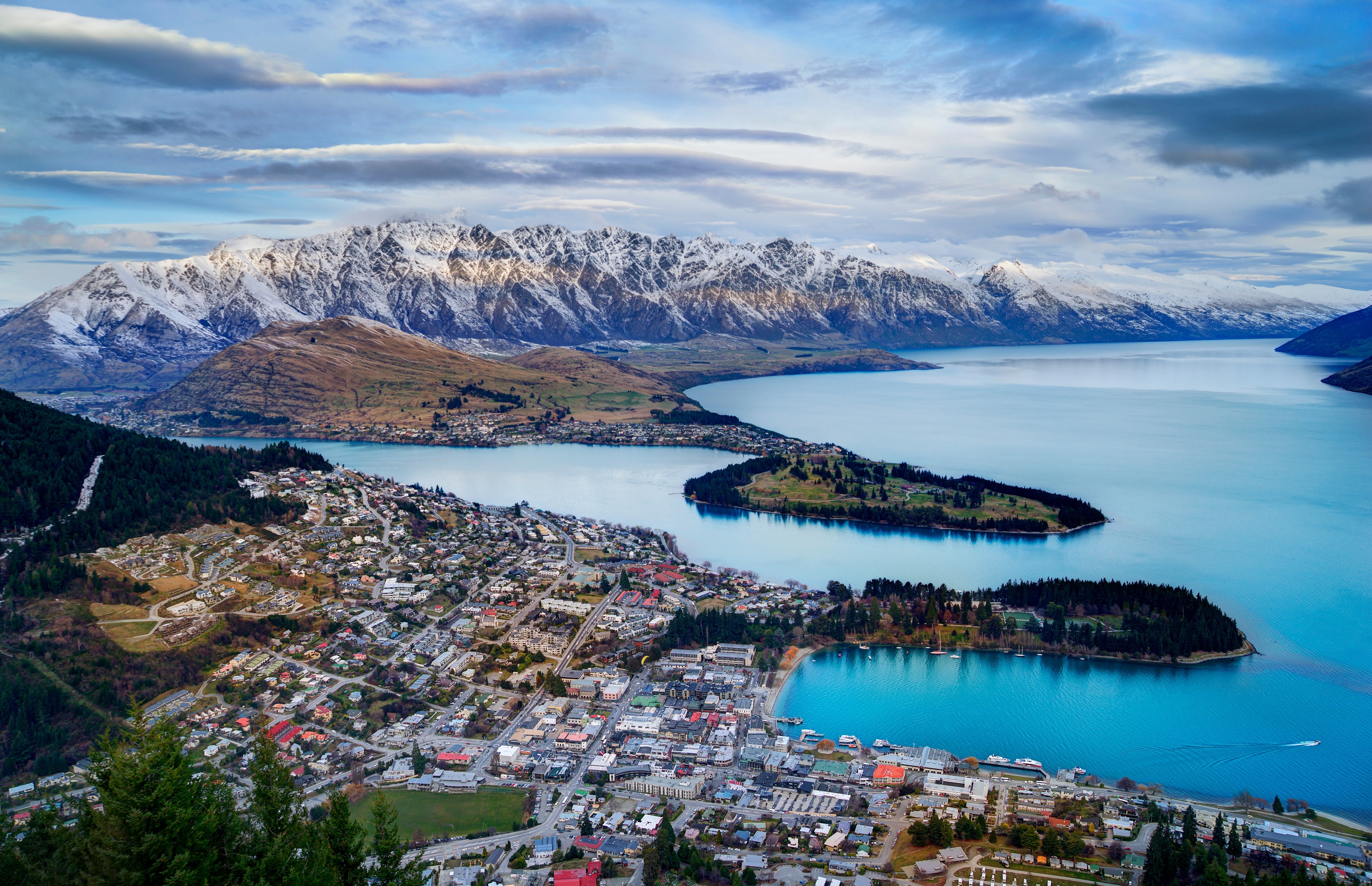 Queenstown and snow-capped mountains overlooking a lake HD Wallpaper