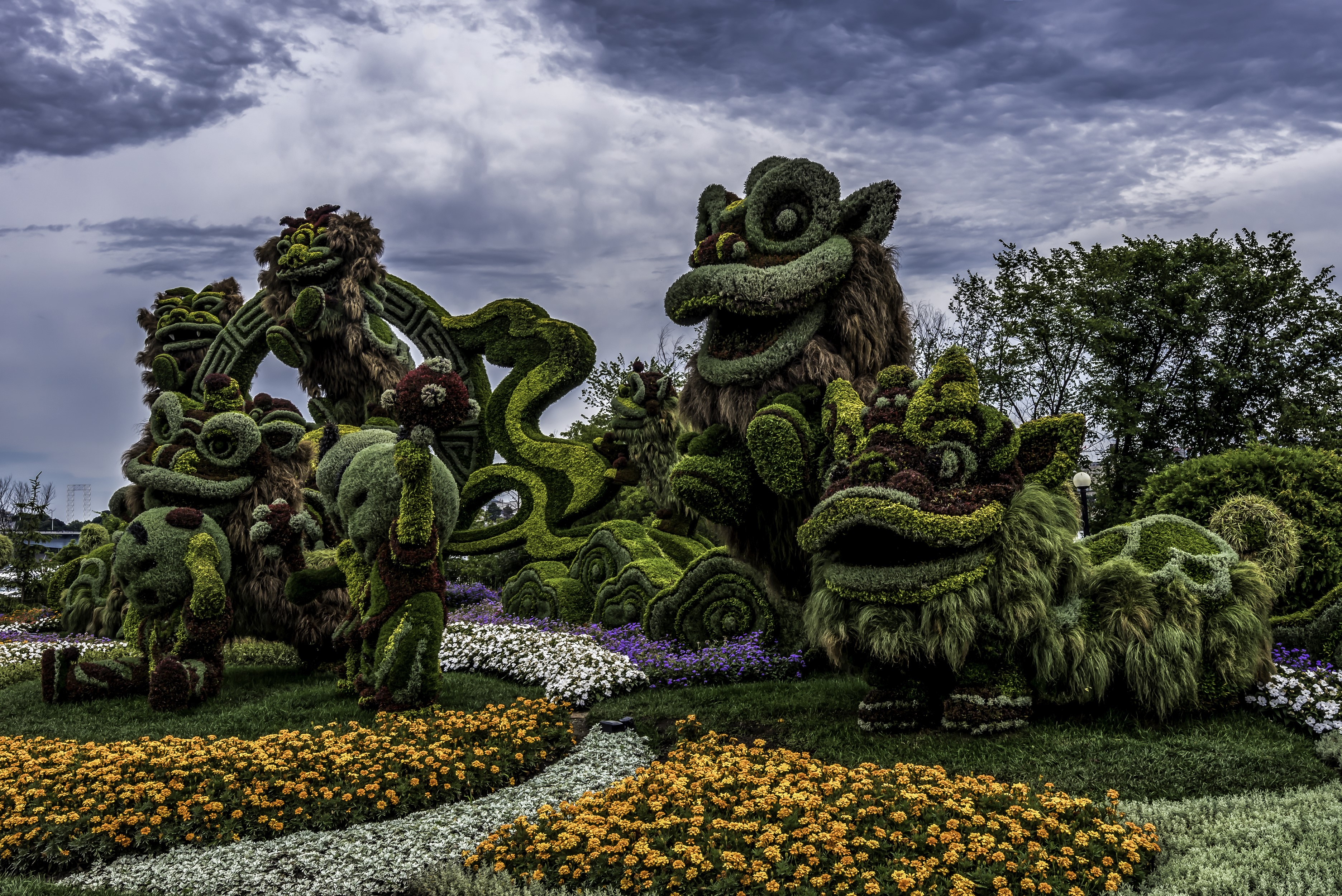 Topiary sculptures of dragons and other mythical creatures in a park HD Wallpaper