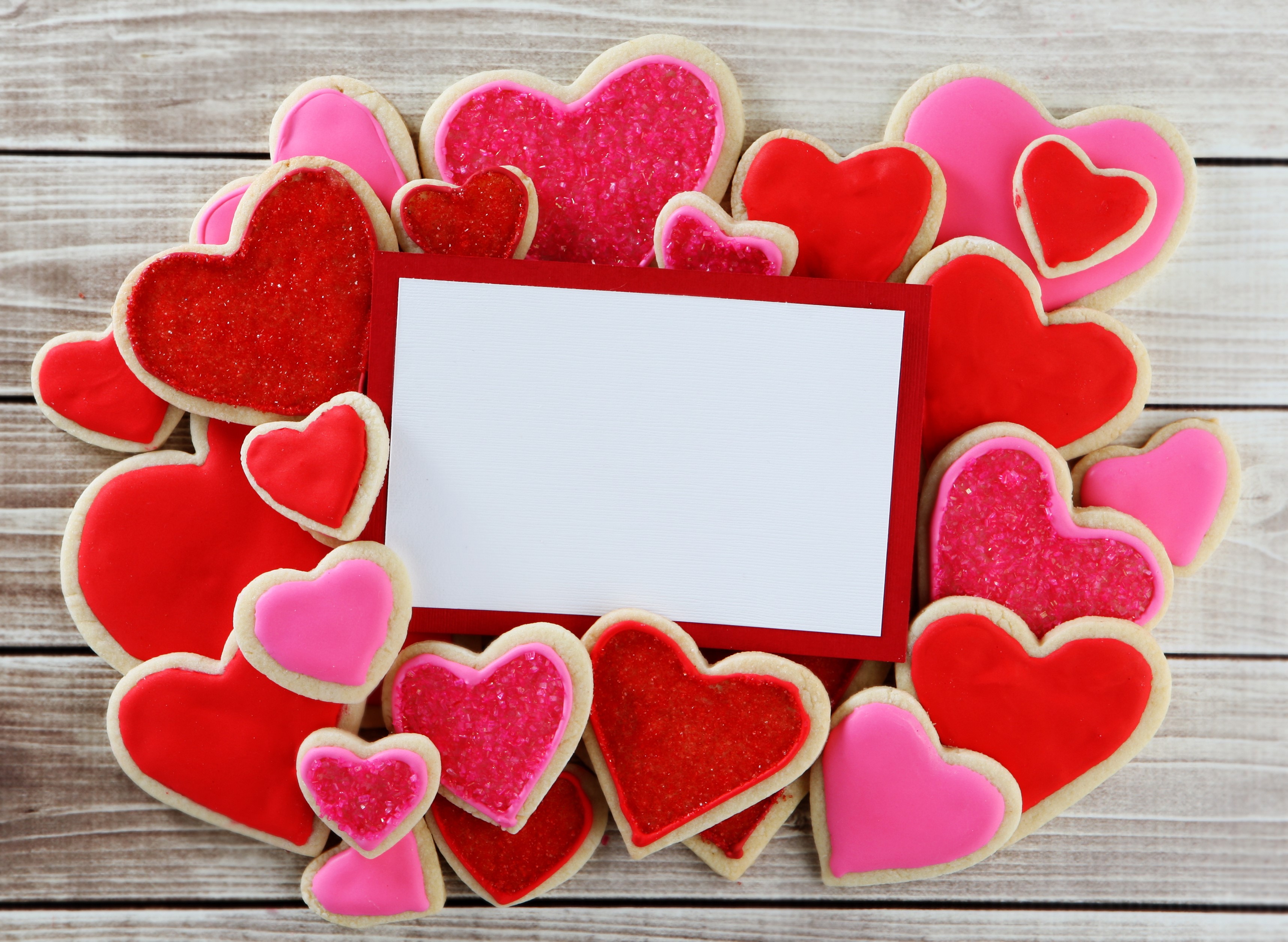 Heart-shaped cookies surrounding a blank card on wood HD Wallpaper