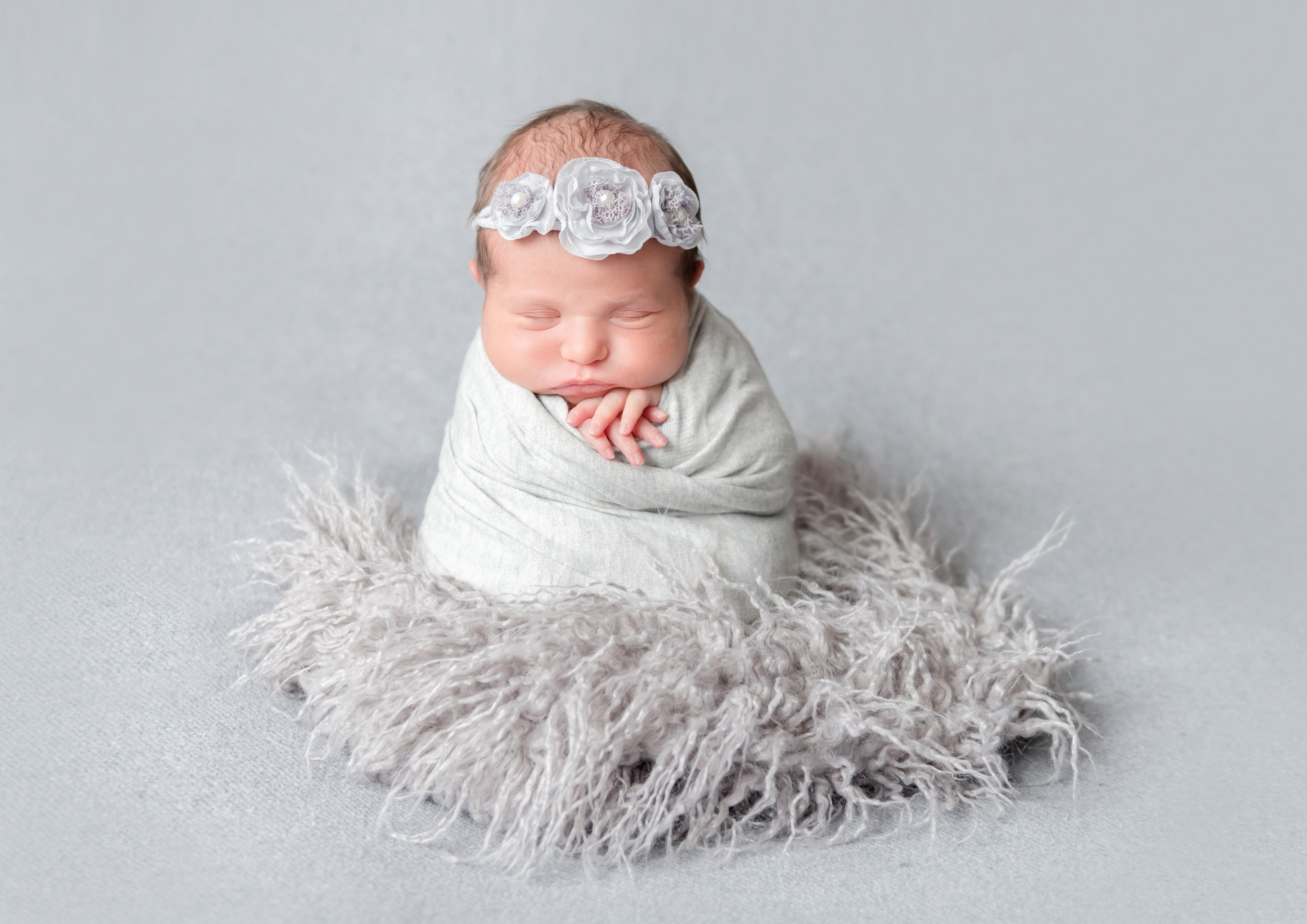 Newborn baby girl wrapped in a blanket with a floral headband HD Wallpaper