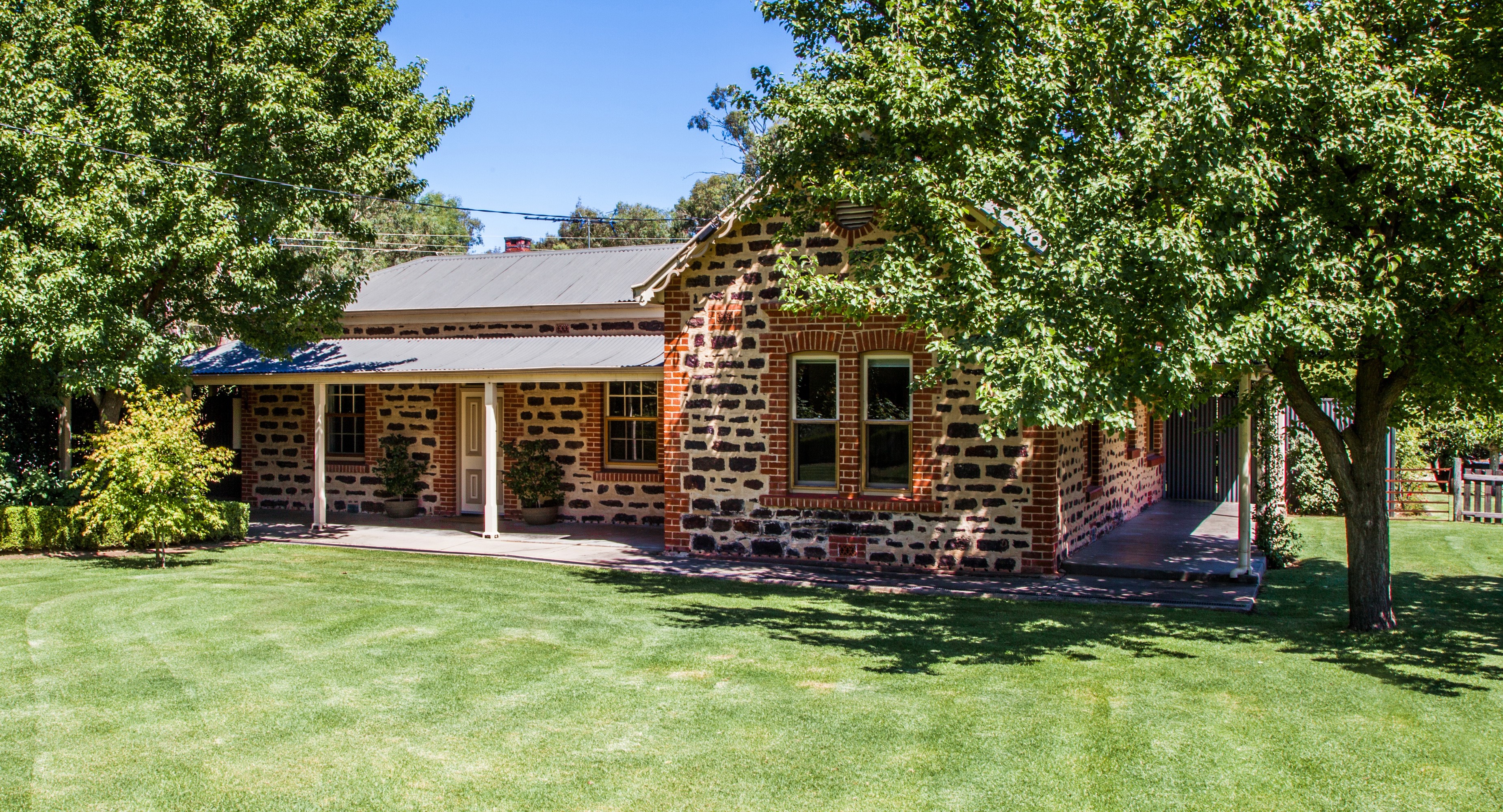 Stone and brick house with a covered porch and lawn HD Wallpaper