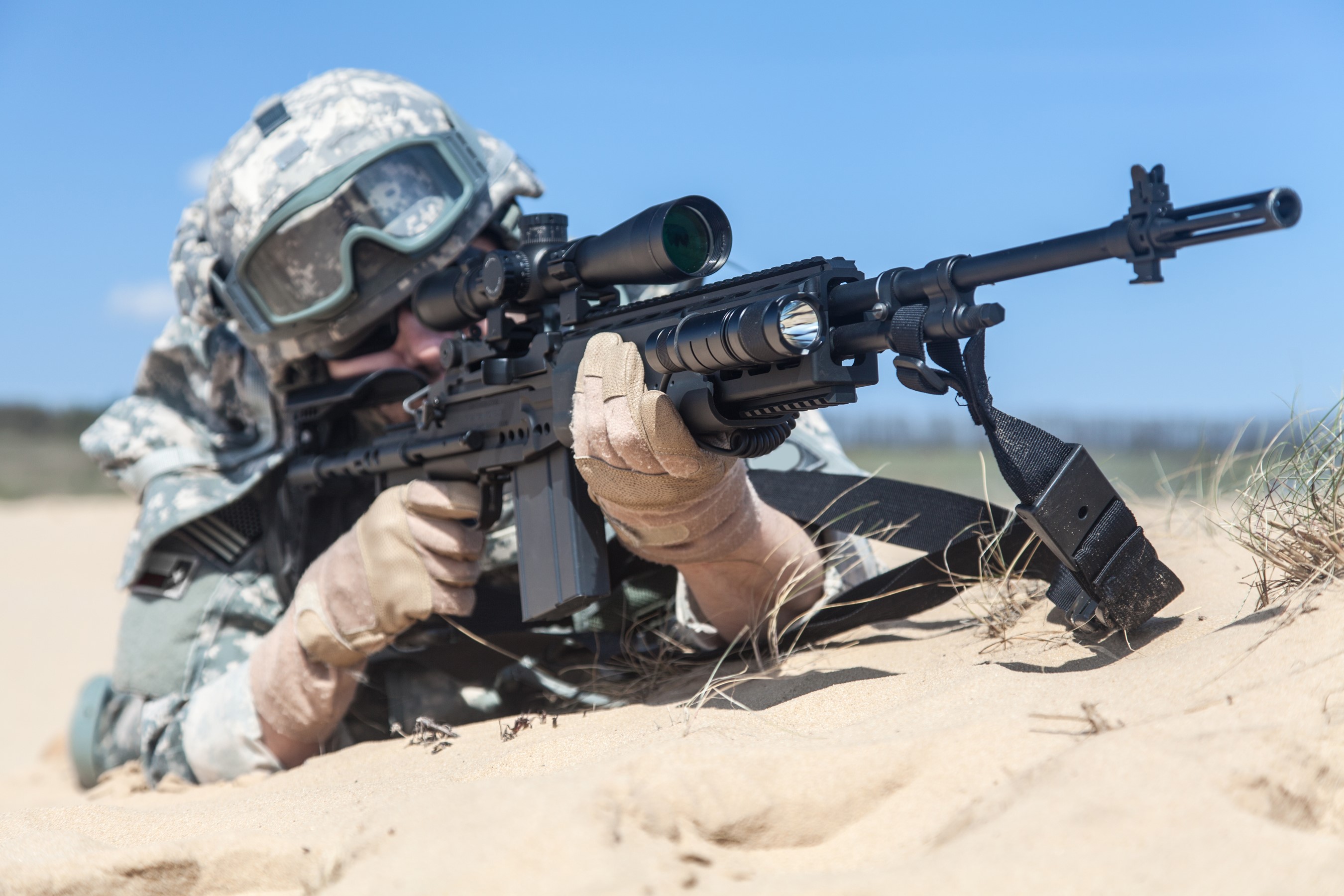Soldier aiming an assault rifle in the sand HD Wallpaper