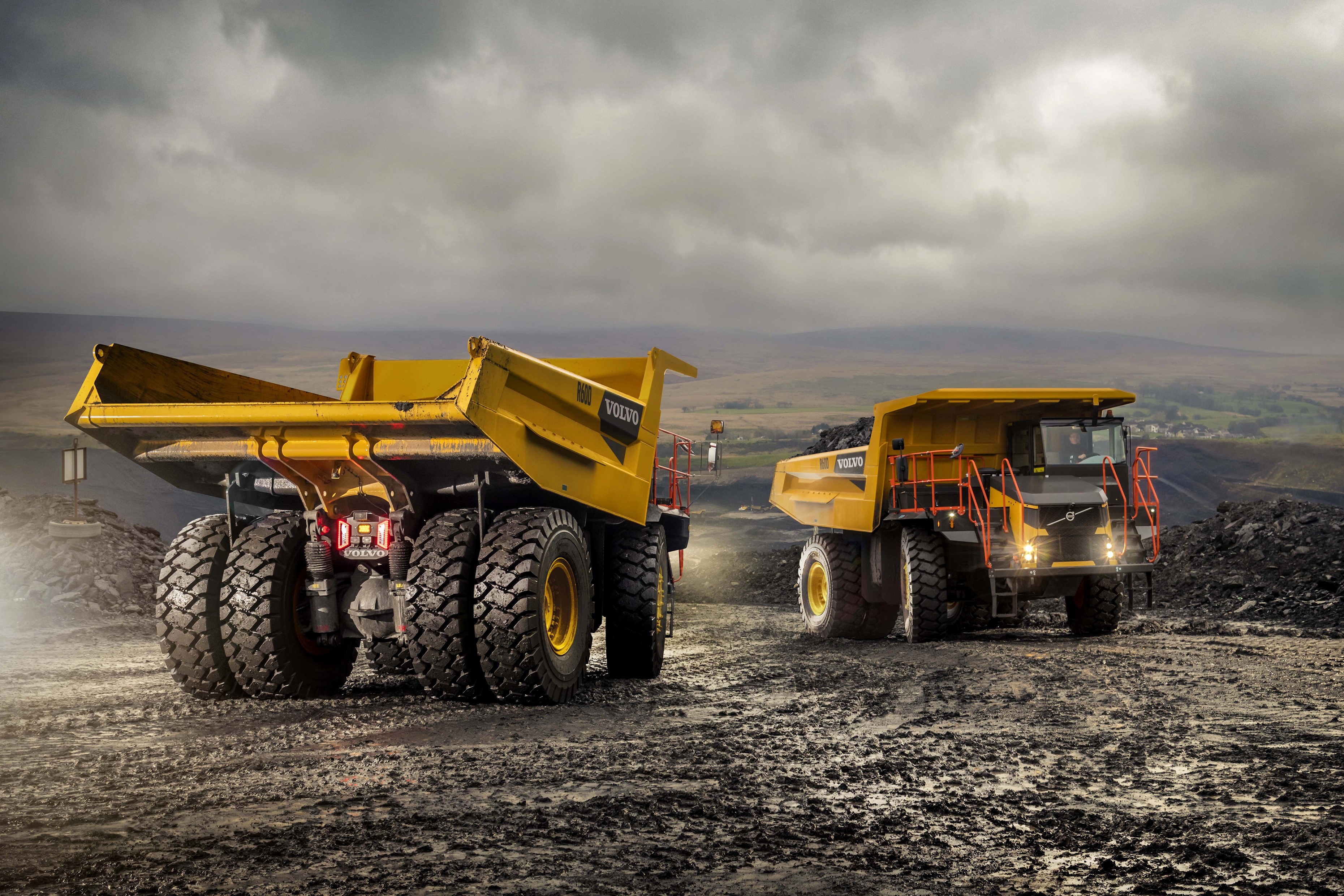 Two Volvo R60D articulated dump trucks in a quarry HD Wallpaper