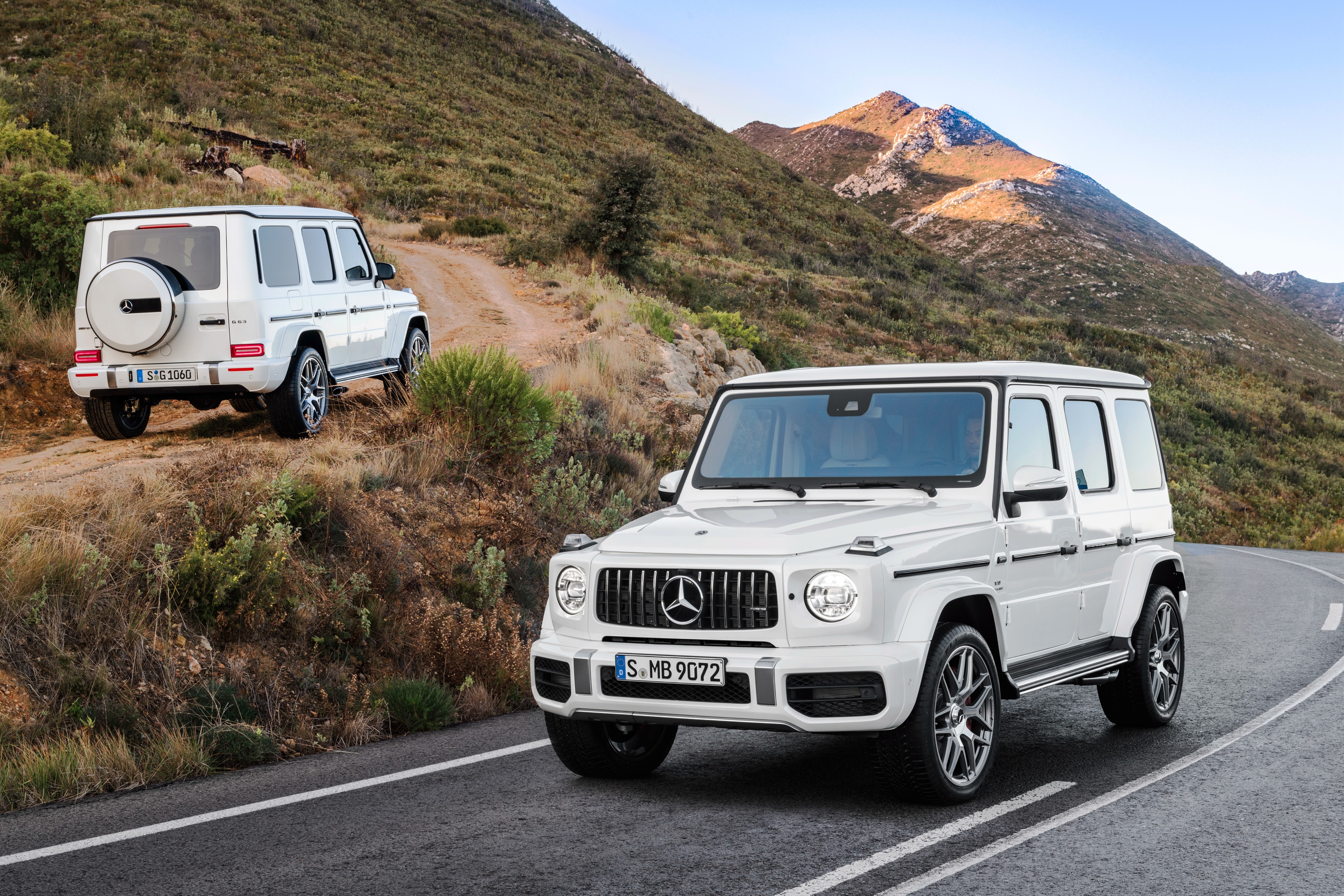 Two white Mercedes-Benz G-Class cars on a mountain road HD Wallpaper