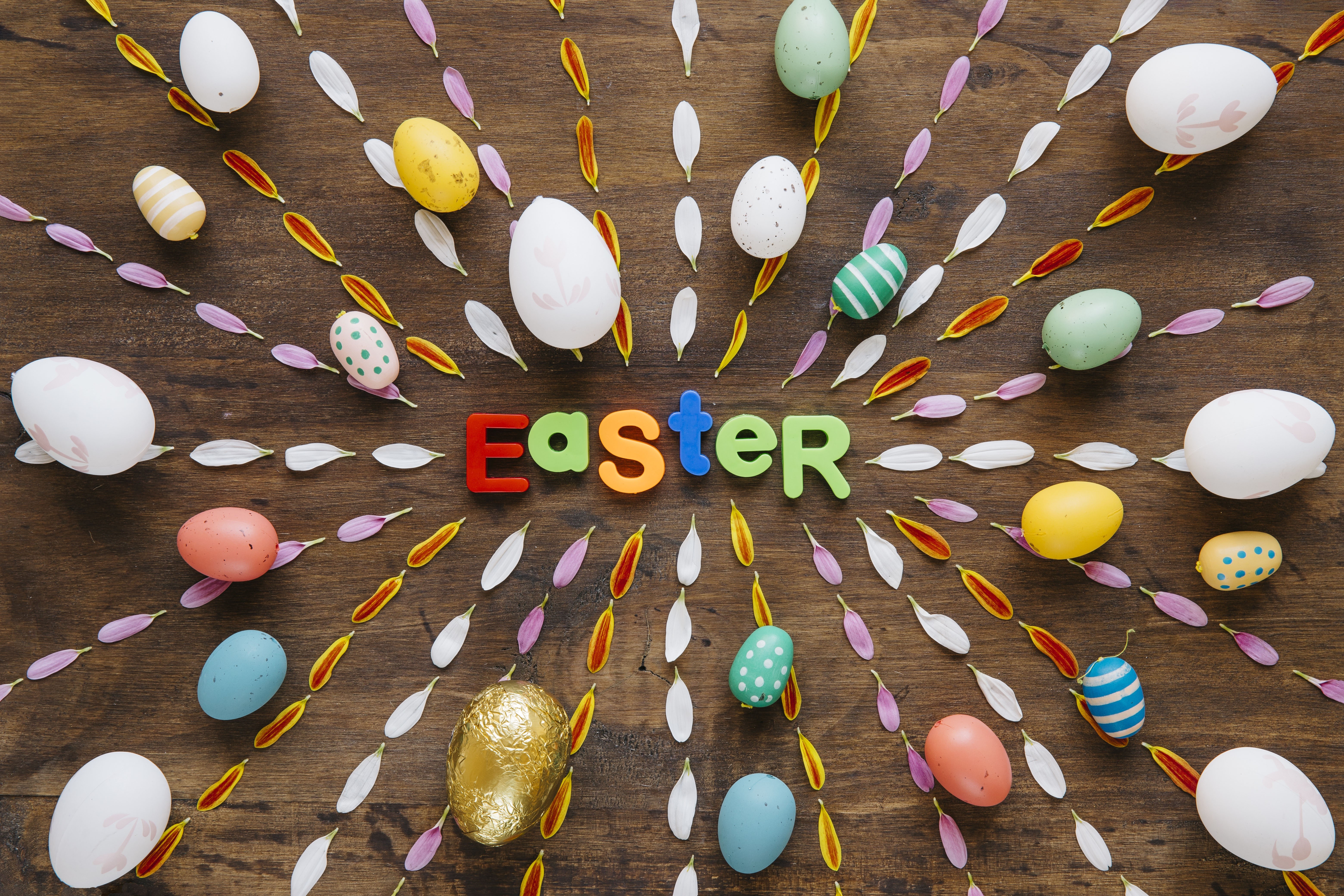 Easter word with eggs and petals on wooden background HD Wallpaper