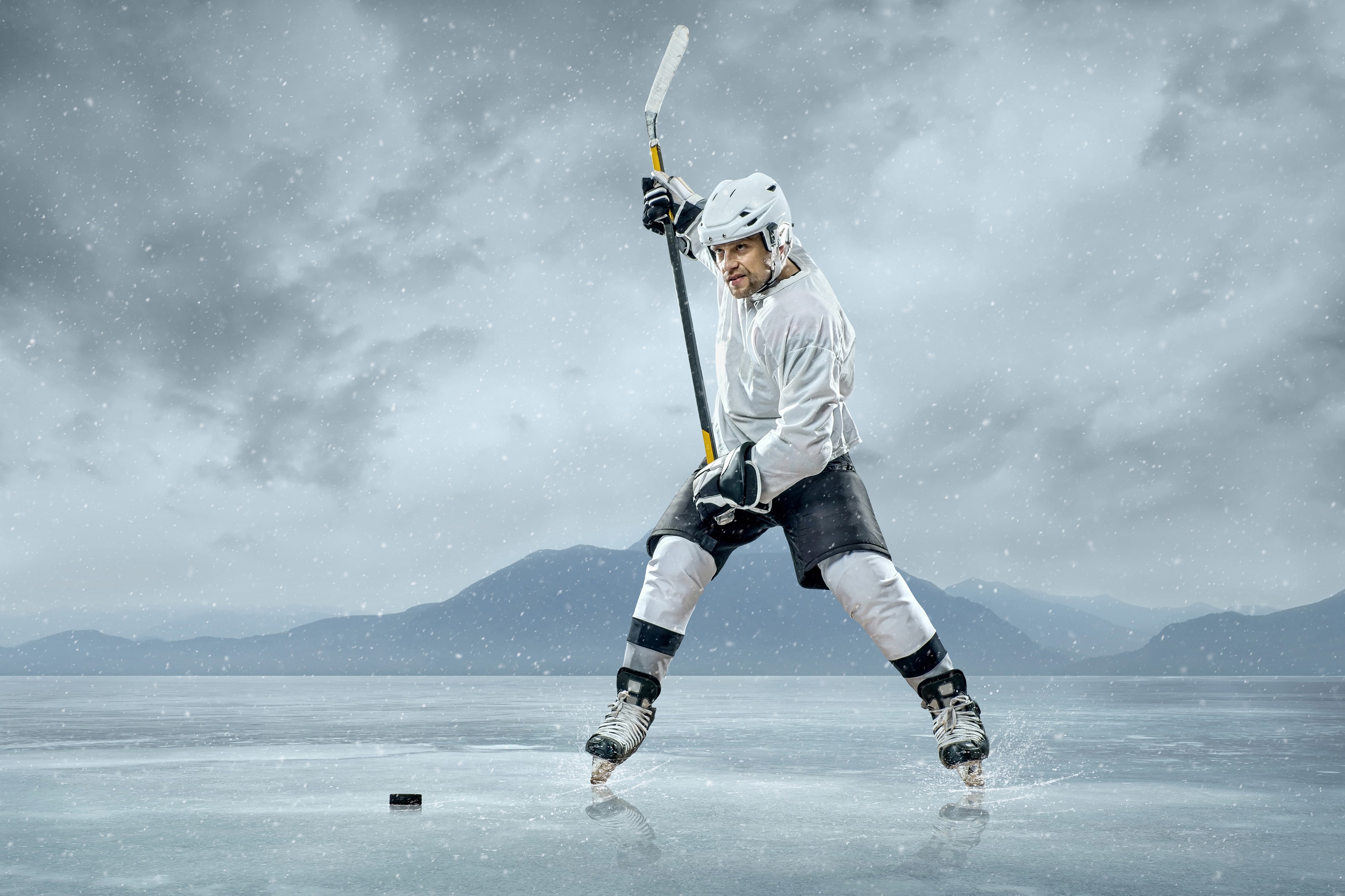 Man playing hockey on a frozen lake HD Wallpaper
