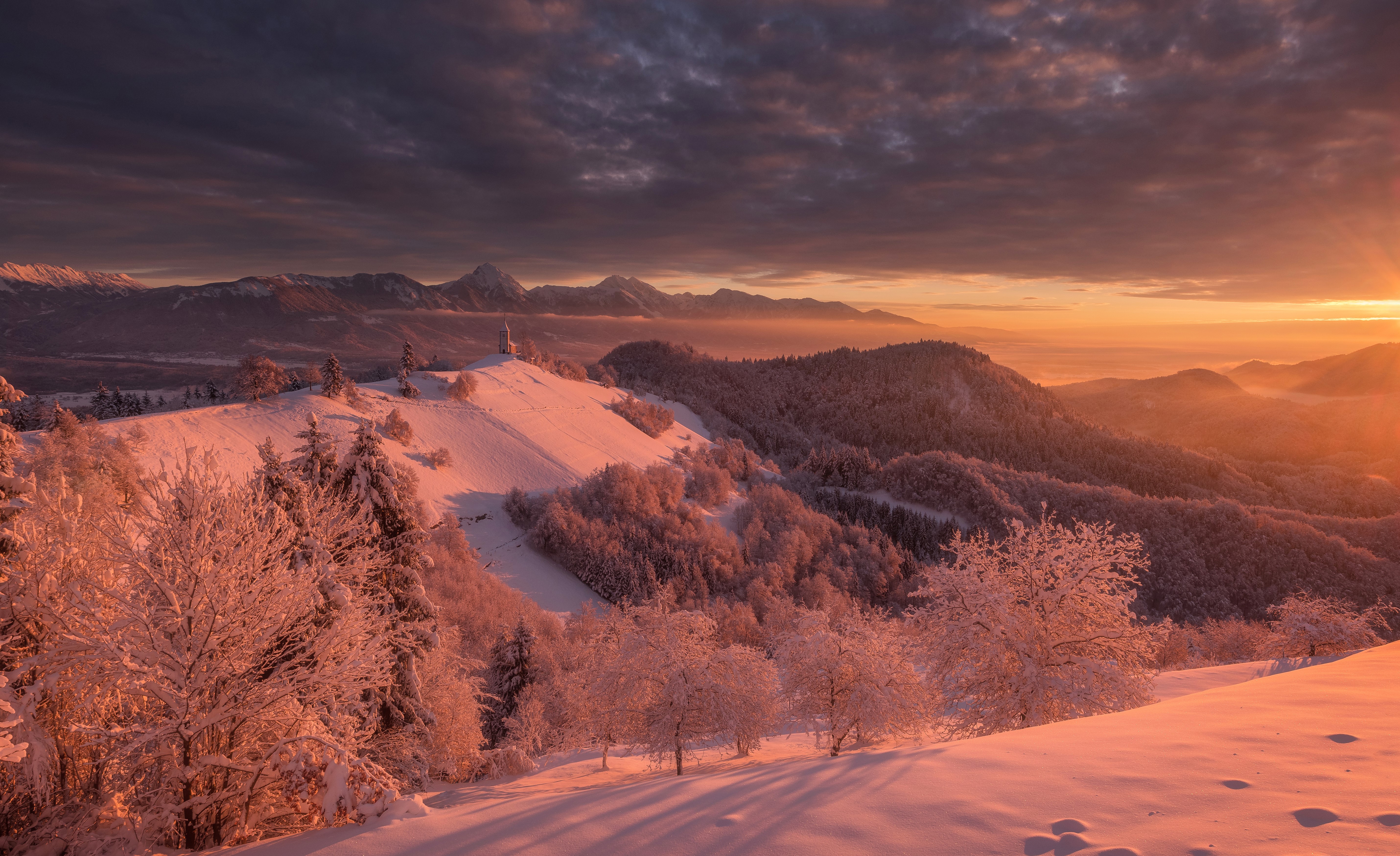Winter sunrise over Radovljica, Slovenia with snow-covered hills HD Wallpaper