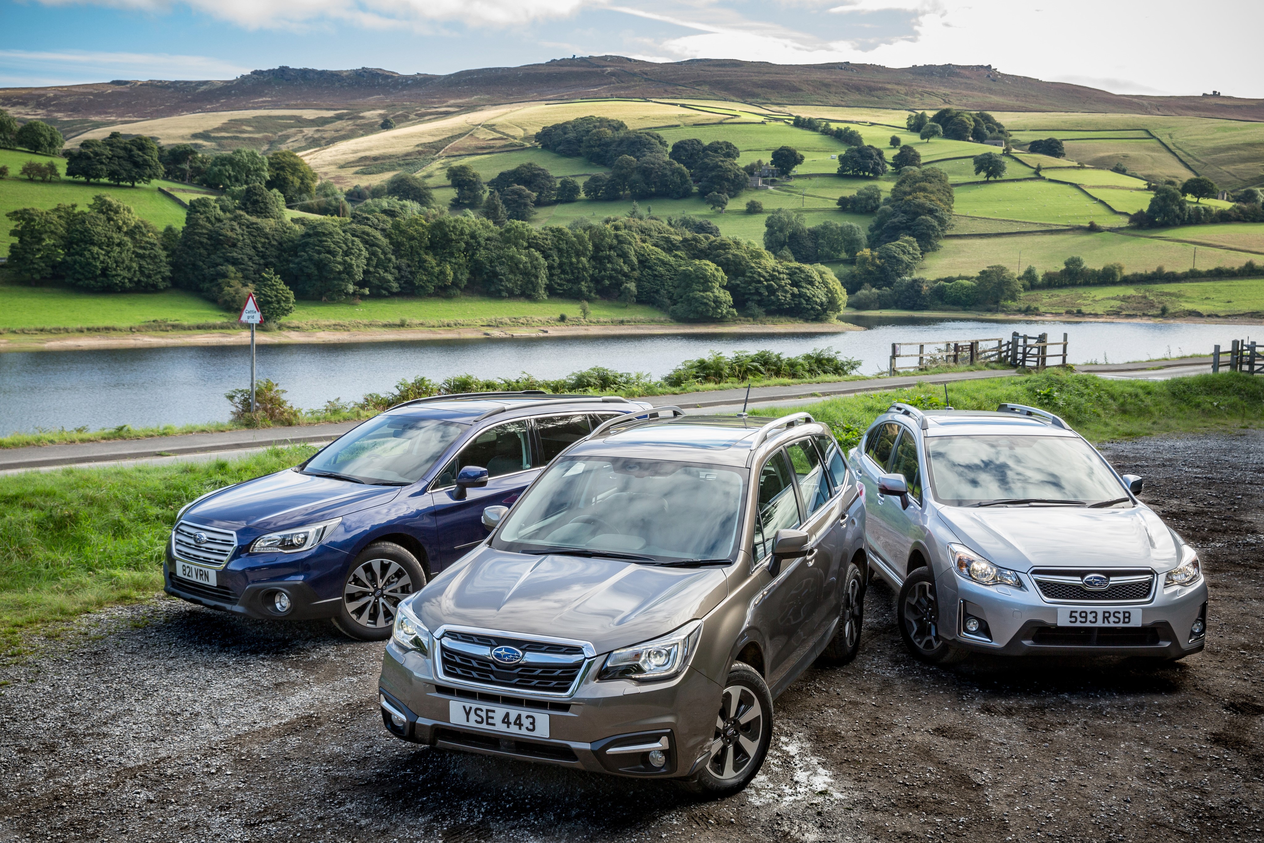 Three Subaru SUVs parked by a reservoir HD Wallpaper