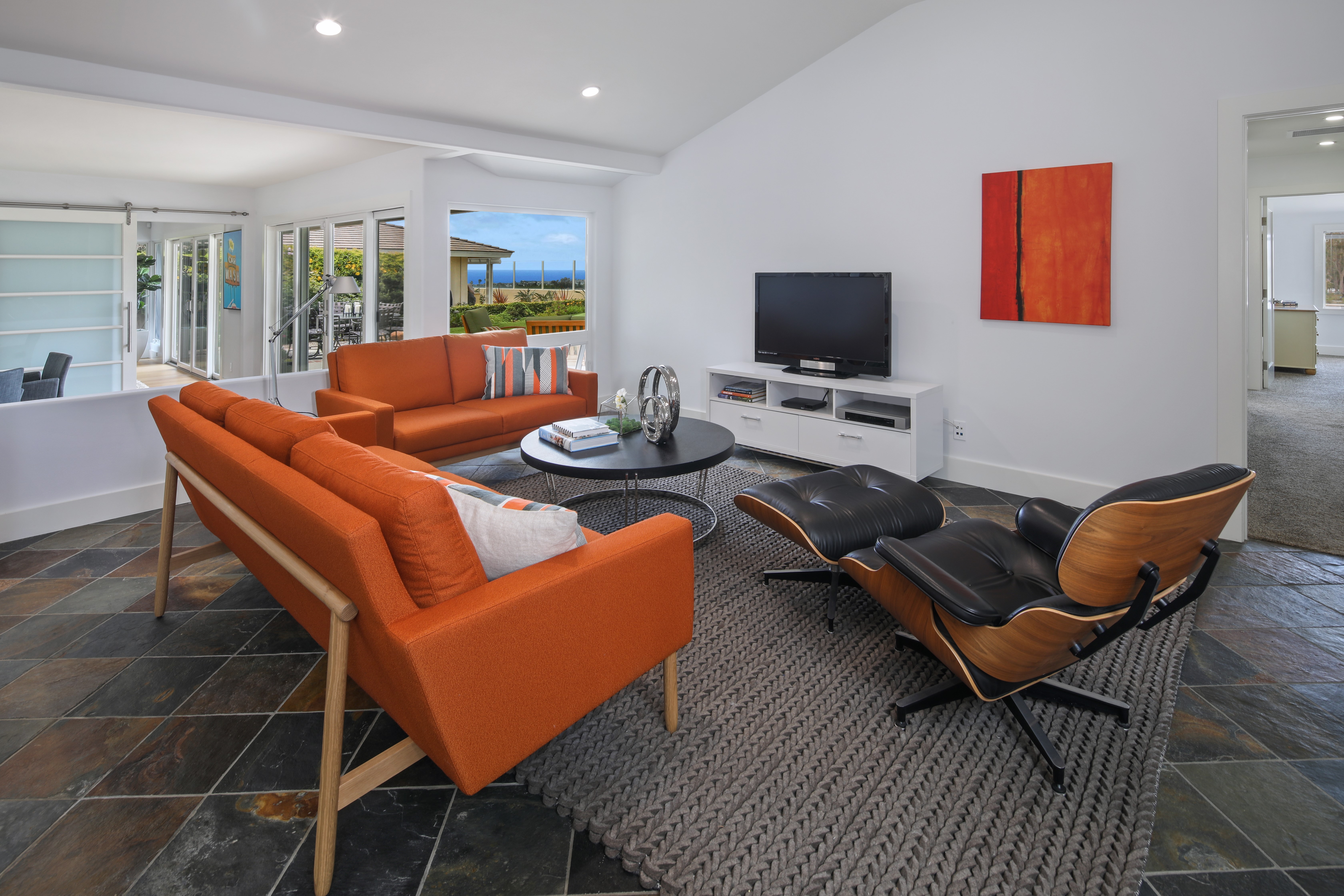 Living room with orange sofas and Eames chair HD Wallpaper