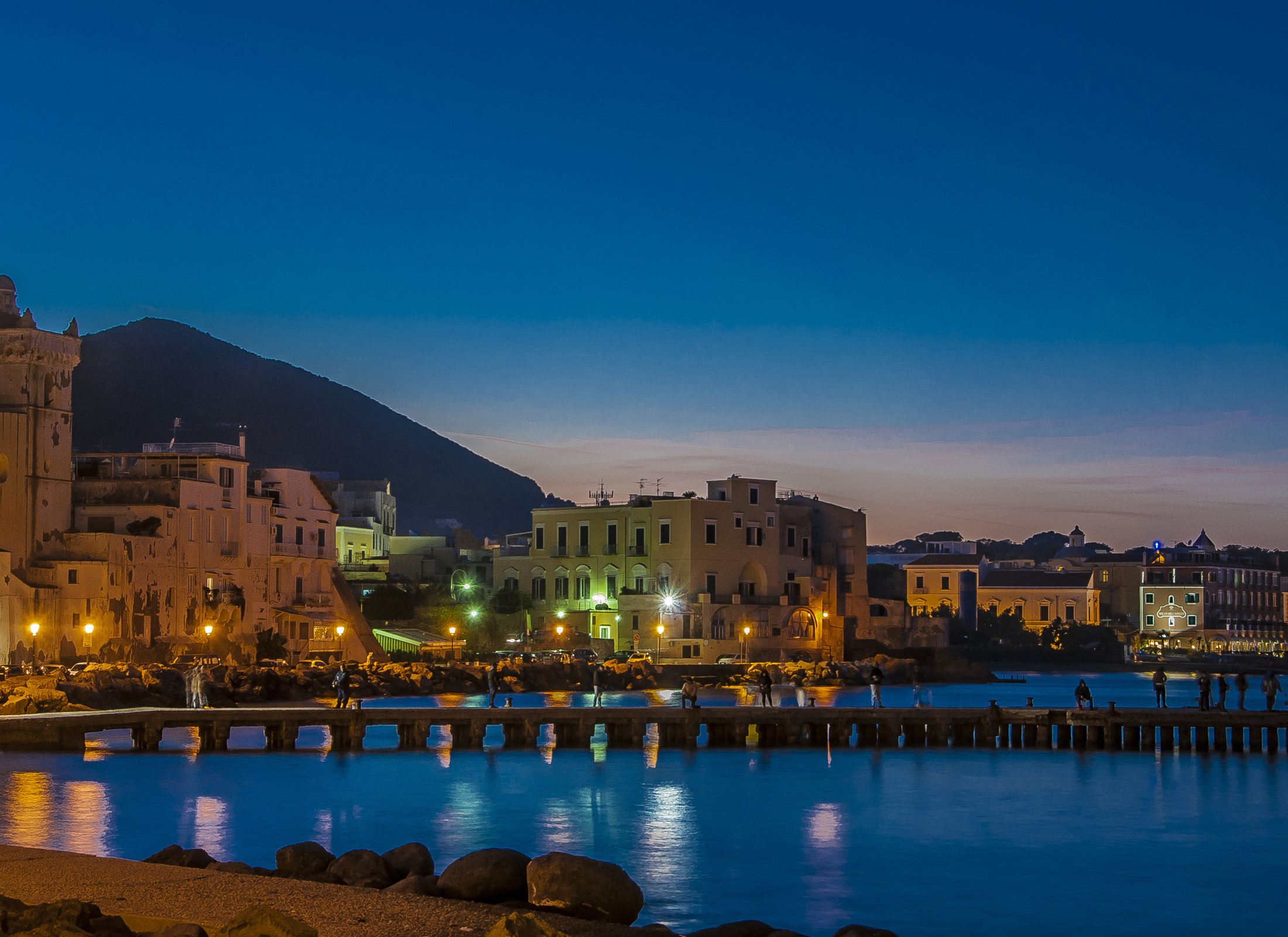 Ischia Ponte, Italy at dusk with illuminated buildings and a pier HD Wallpaper
