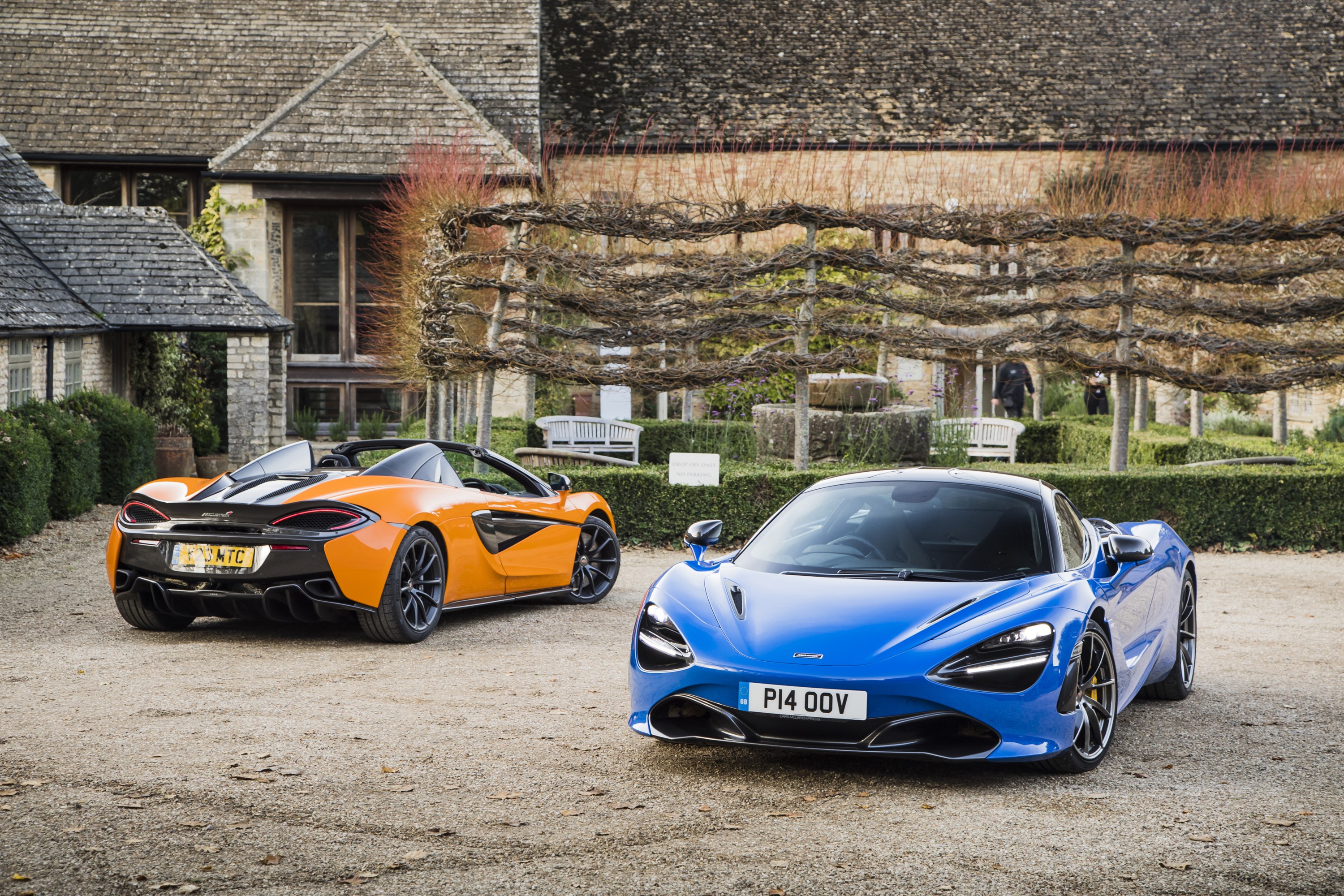Two McLaren sports cars parked outside a building HD Wallpaper