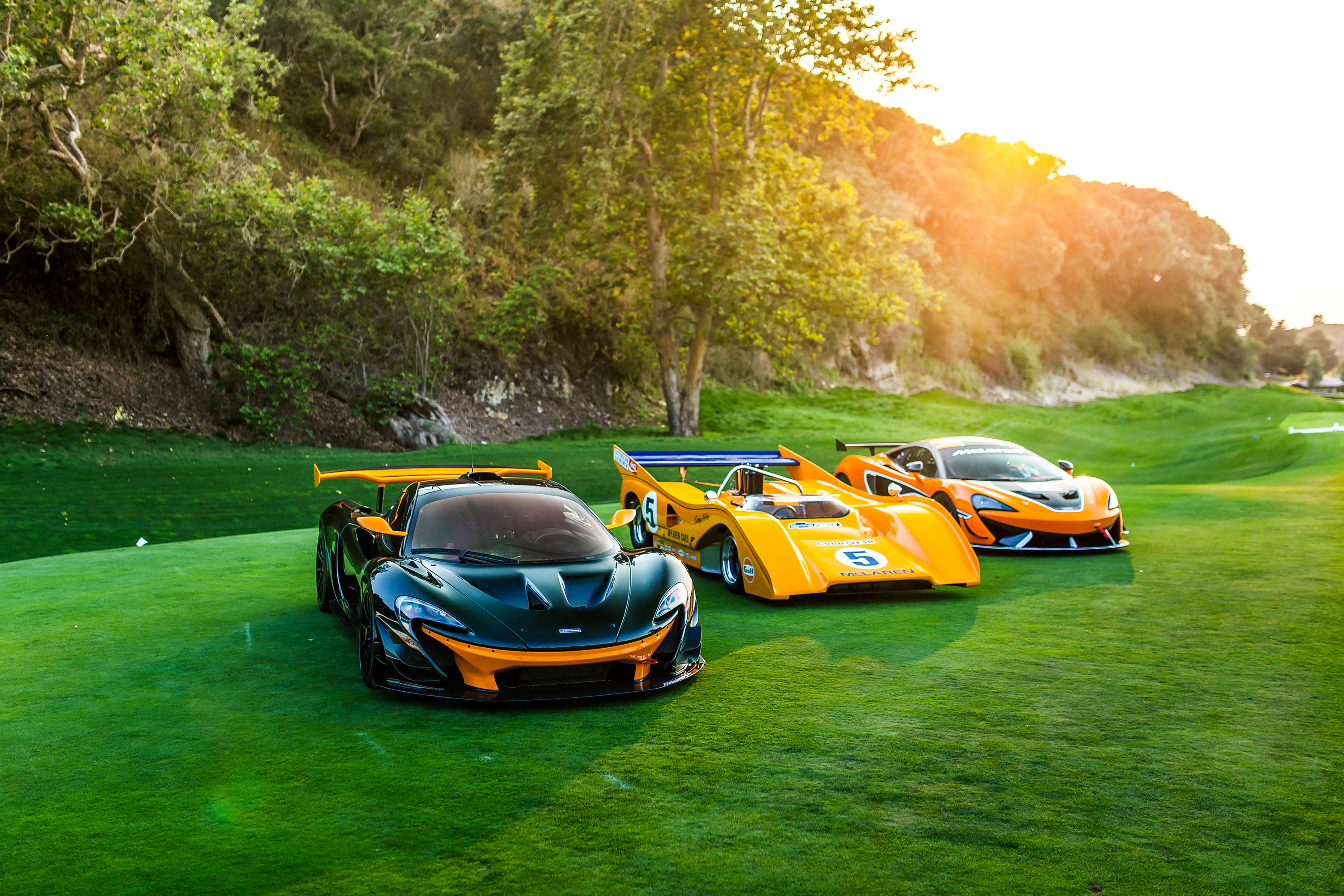 Three McLaren sports cars on a golf course HD Wallpaper