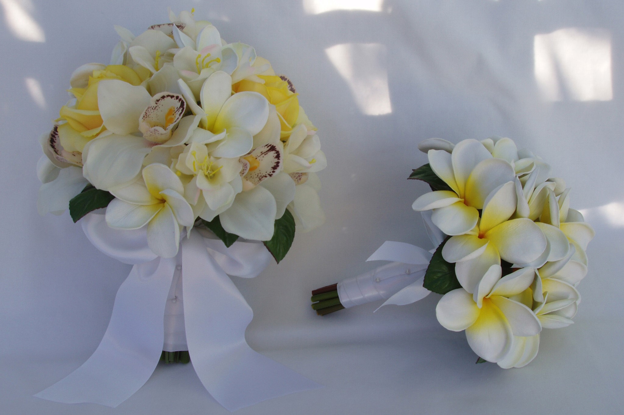 Two bouquets of plumeria and orchids with white ribbons HD Wallpaper