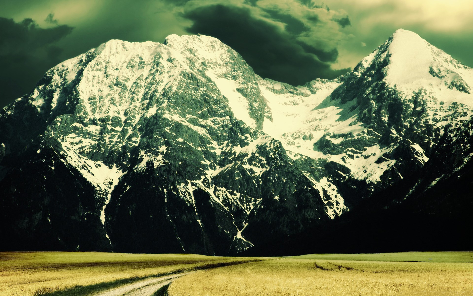 Snow-capped mountains under a dark sky HD Wallpaper