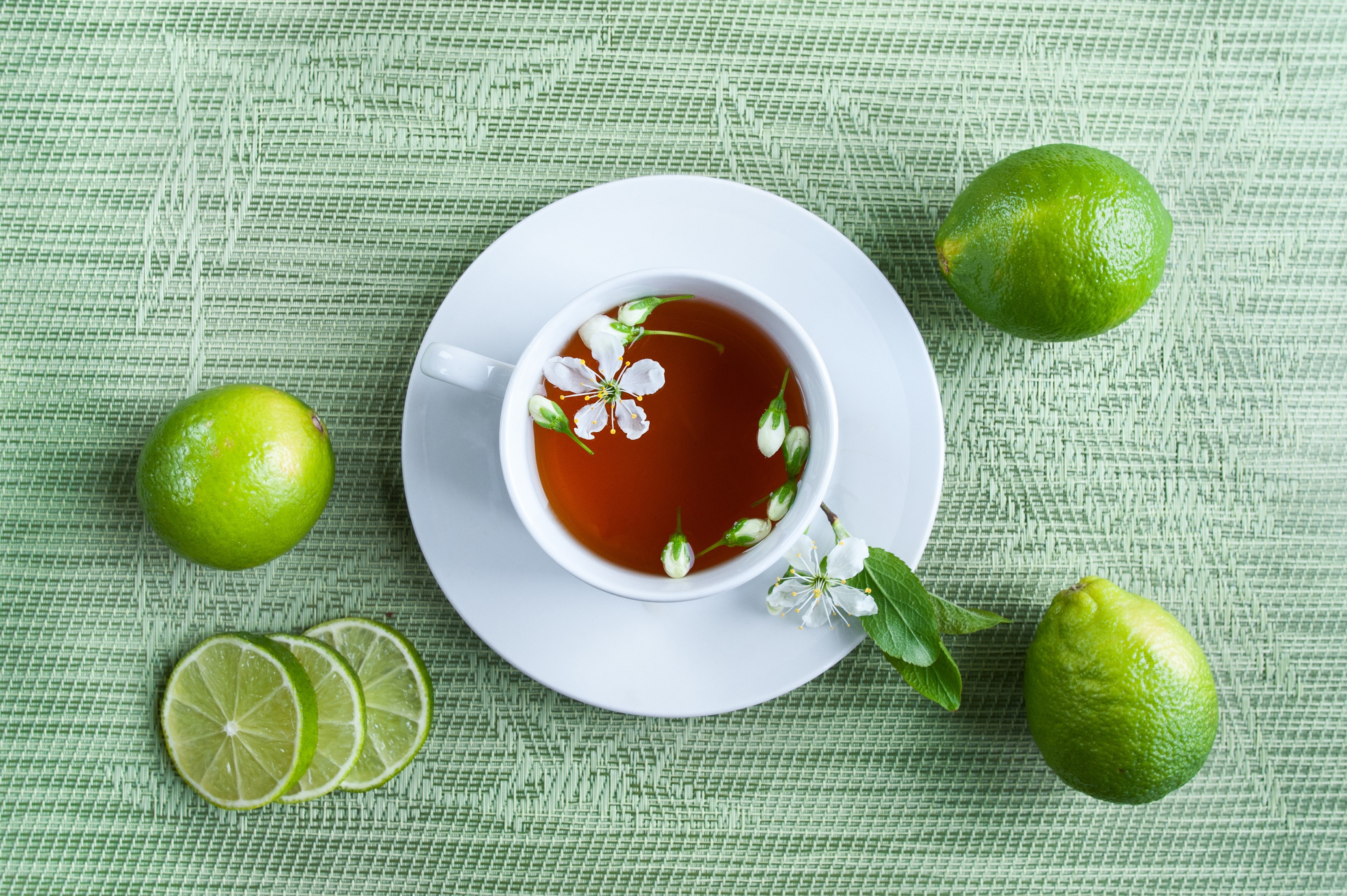Tea with lime and flowers on a green background HD Wallpaper