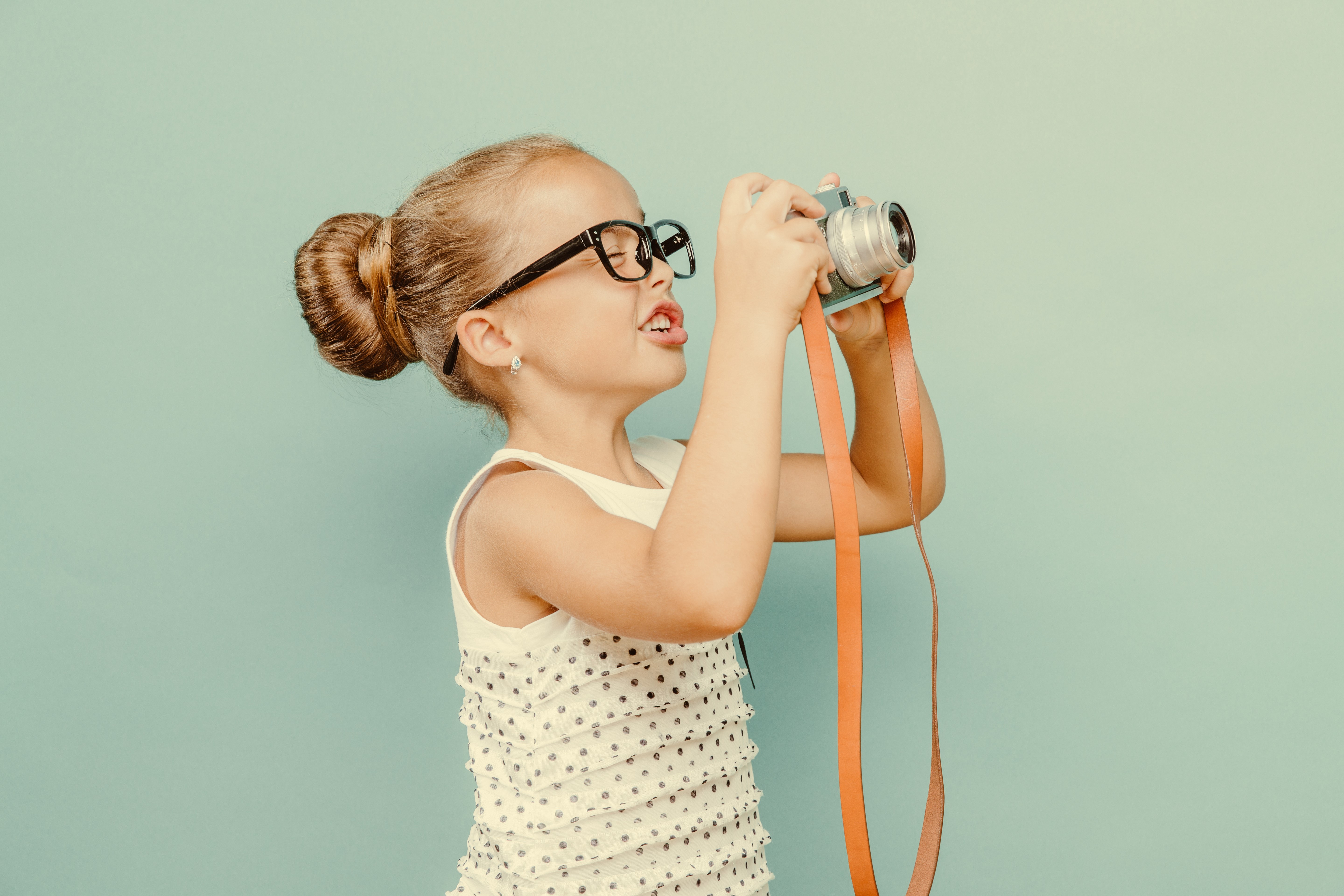 Little girl with glasses taking a picture with a camera HD Wallpaper