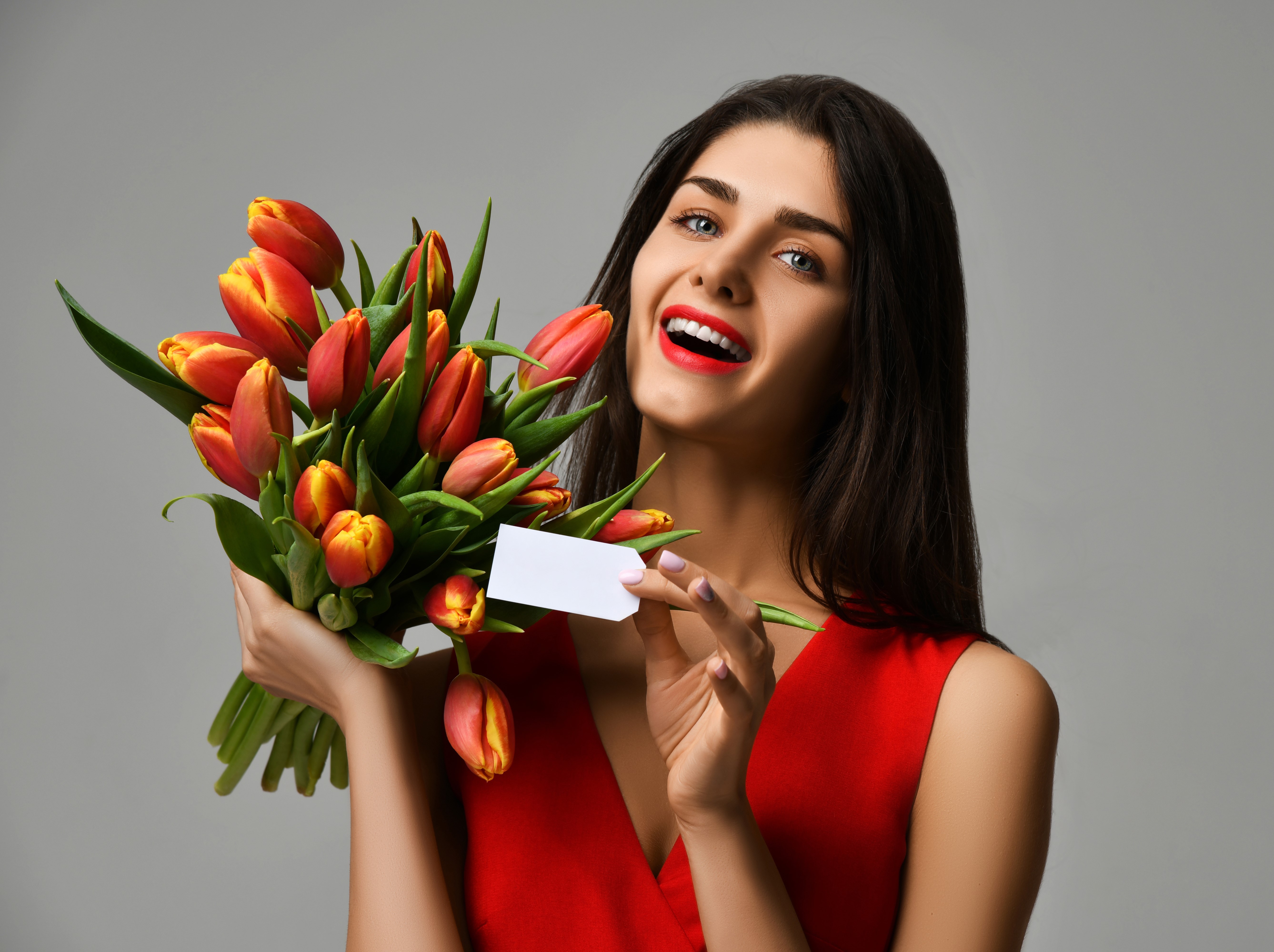 Woman in red dress holding bouquet of tulips with blank card HD Wallpaper