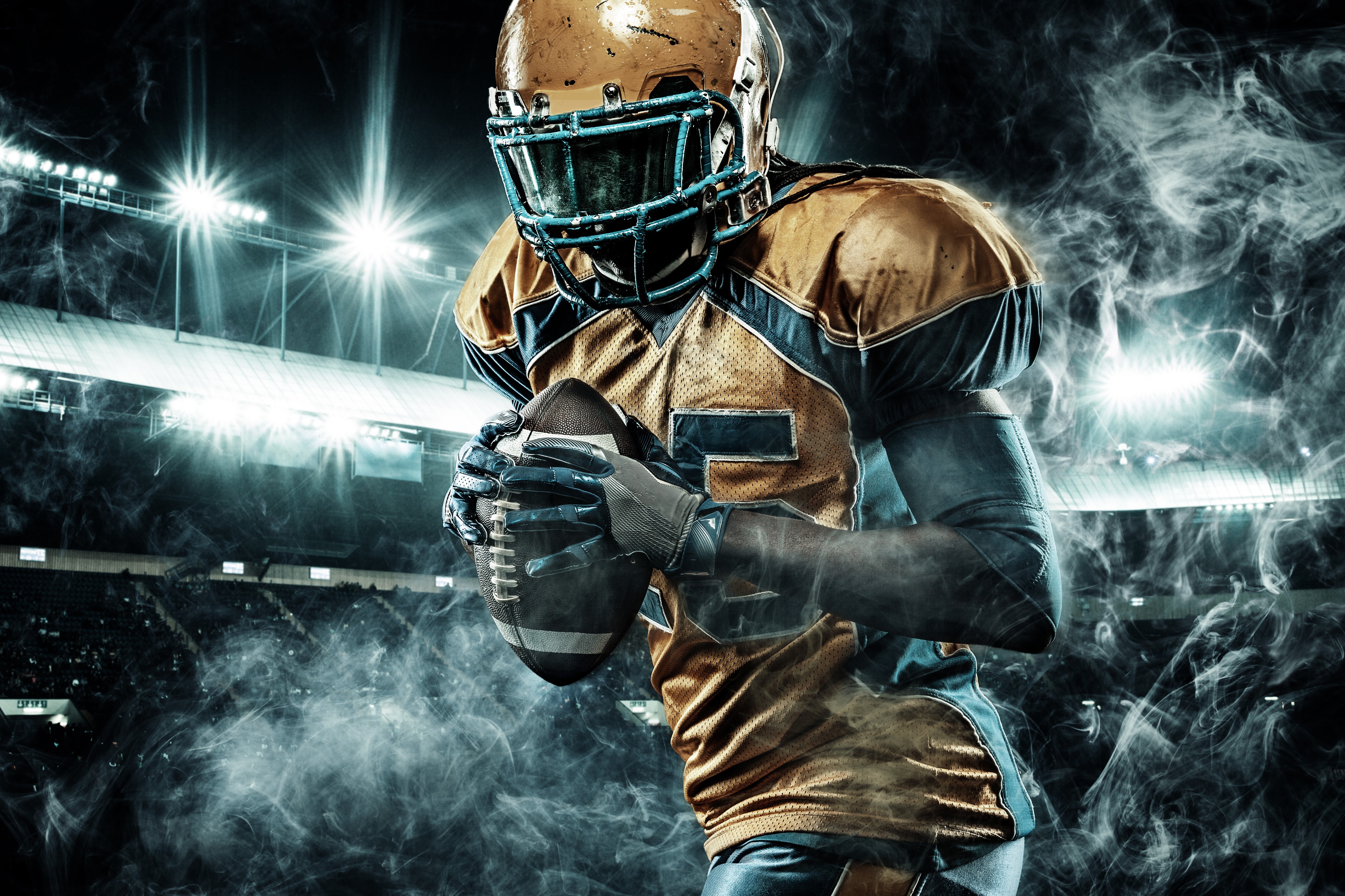 American football player in uniform holding a ball HD Wallpaper
