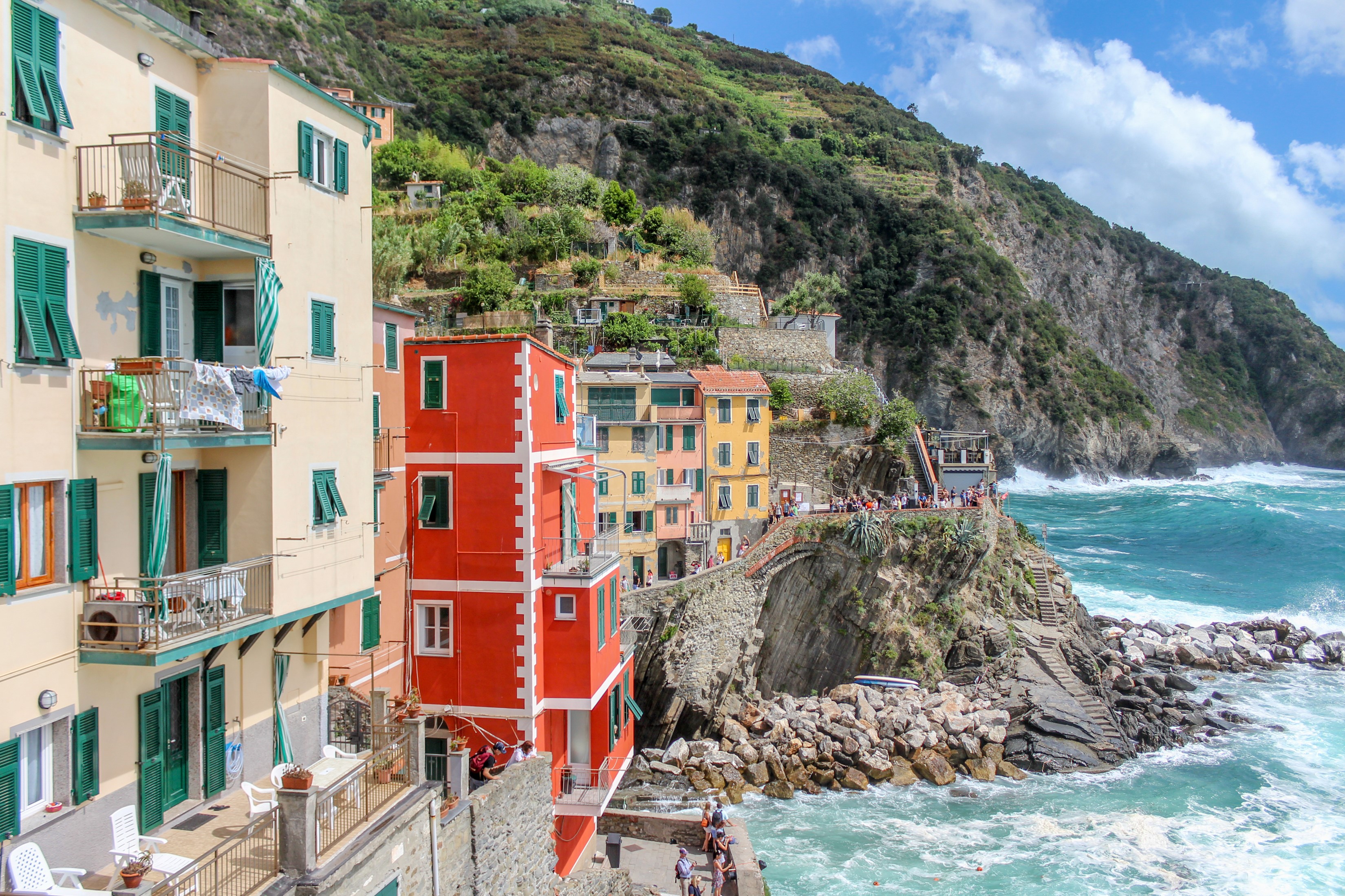 Colorful houses on a cliffside in Riomaggiore, Italy with waves crashing HD Wallpaper