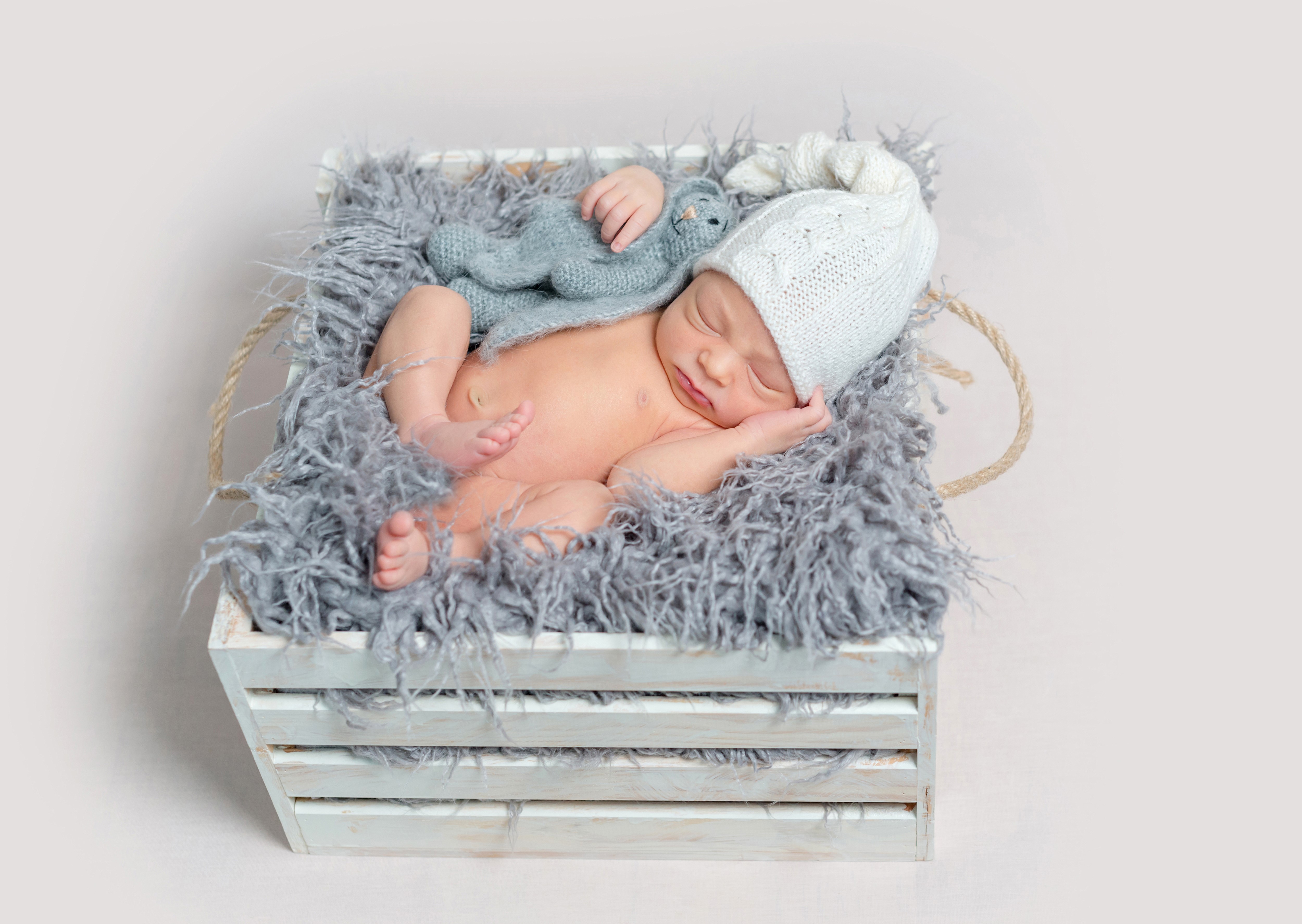 Newborn baby sleeping in a wooden crate with a toy HD Wallpaper