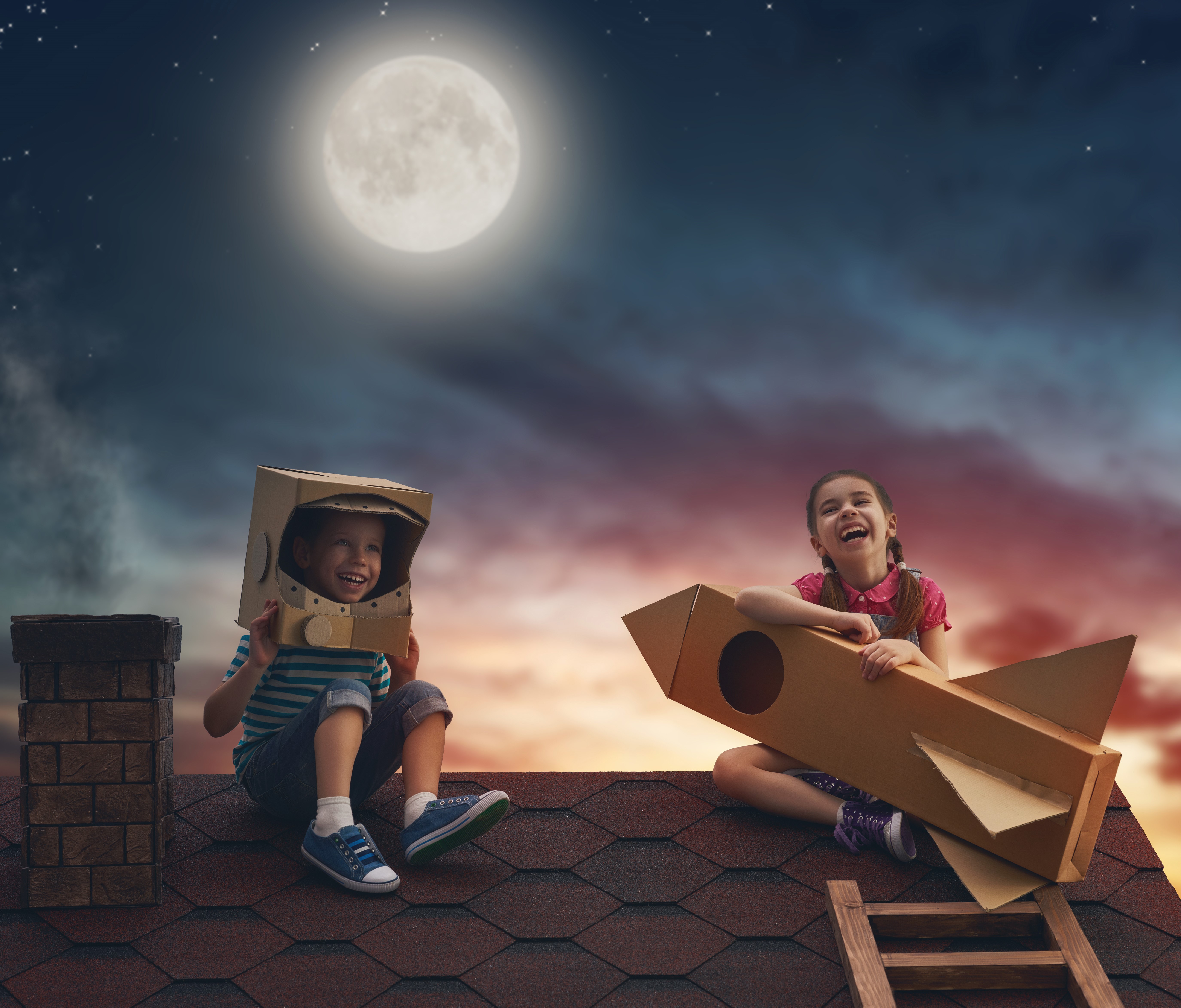Children on a roof with cardboard rocket and helmet at night HD Wallpaper