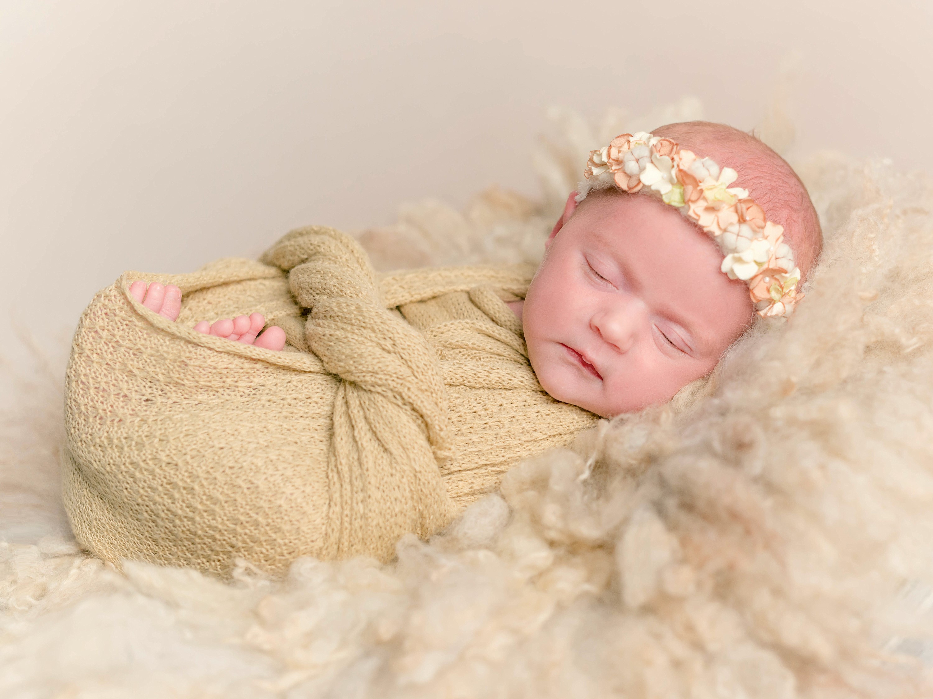 Newborn baby girl sleeping wrapped in a blanket with a flower crown HD Wallpaper