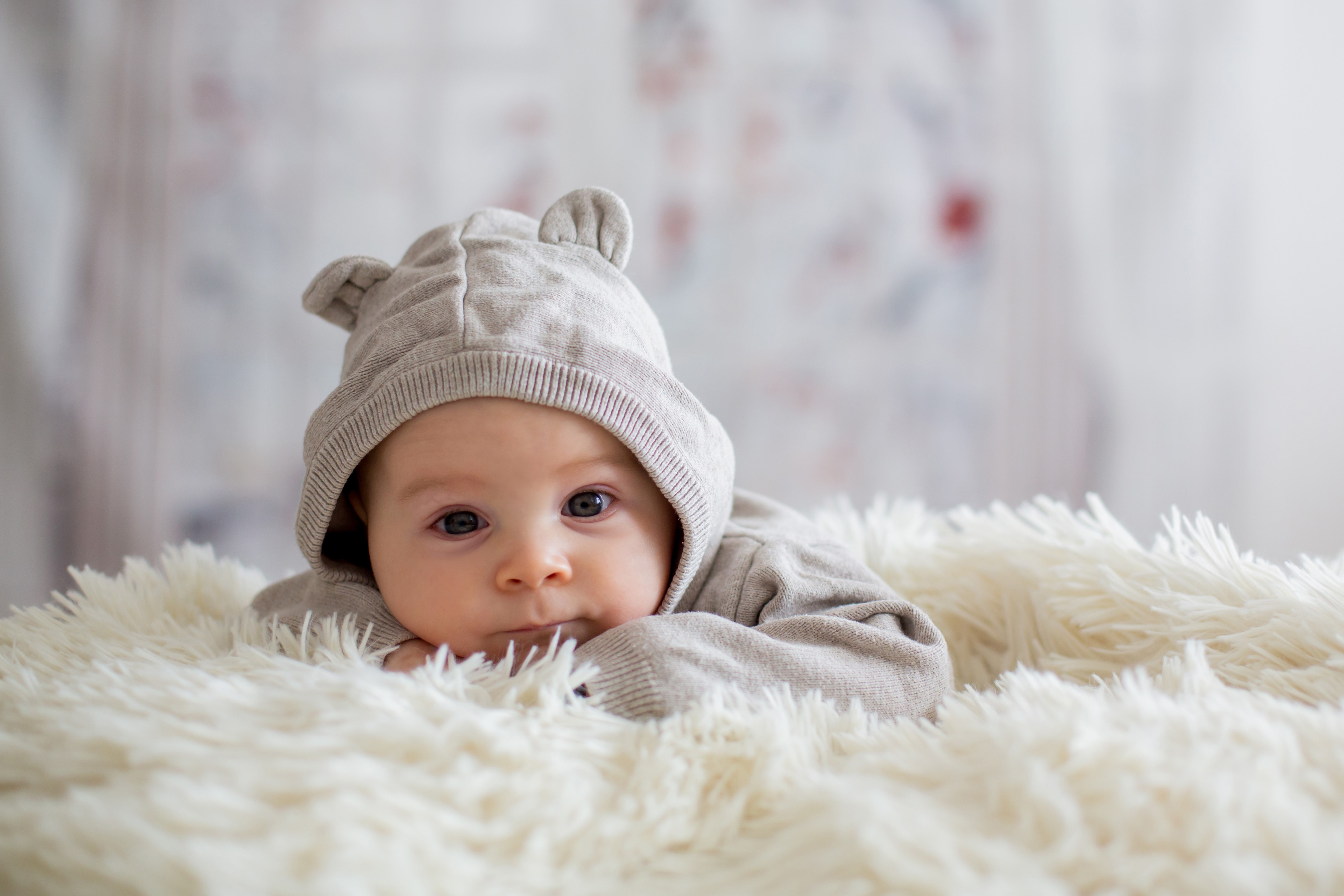 Baby in a bear hat lying on a fluffy blanket HD Wallpaper