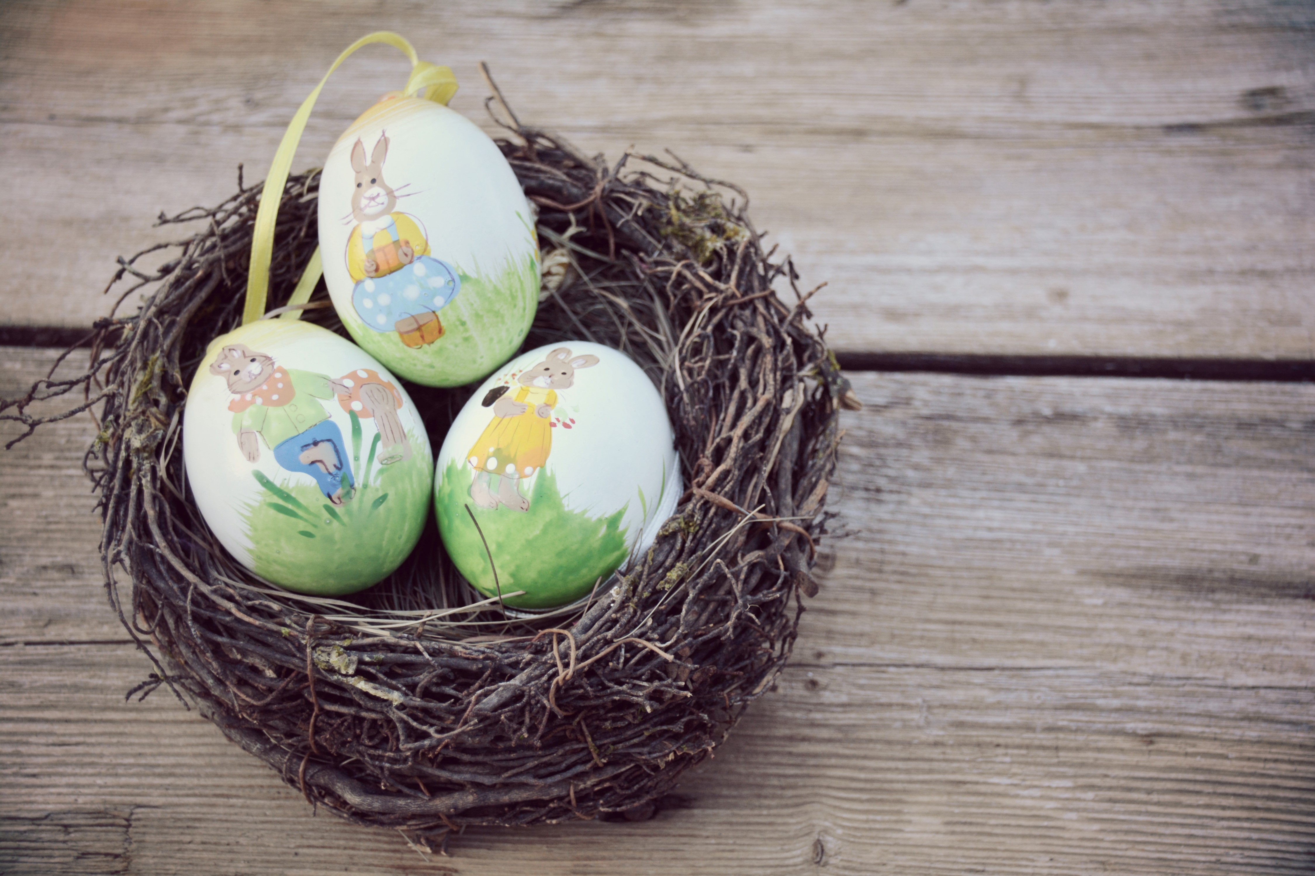 Easter eggs with bunnies in a nest on wood HD Wallpaper