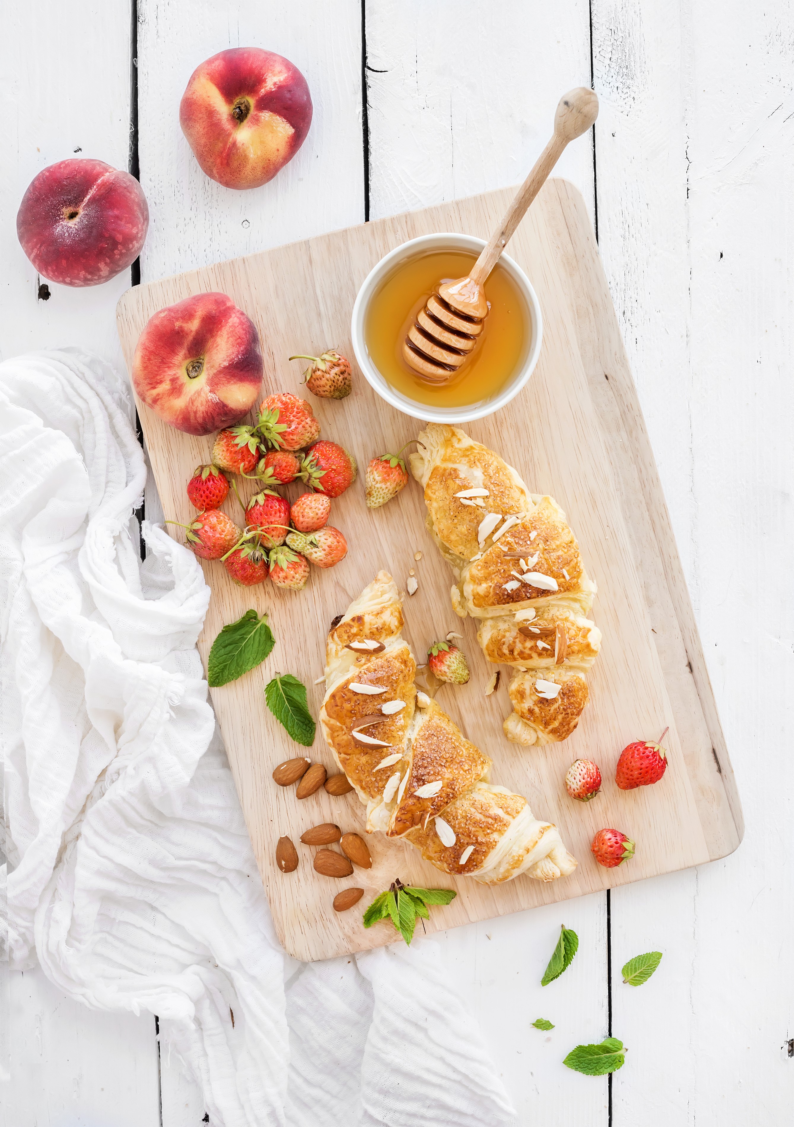 Croissants with peaches, strawberries, honey, and almonds on a cutting board HD Phone Wallpaper