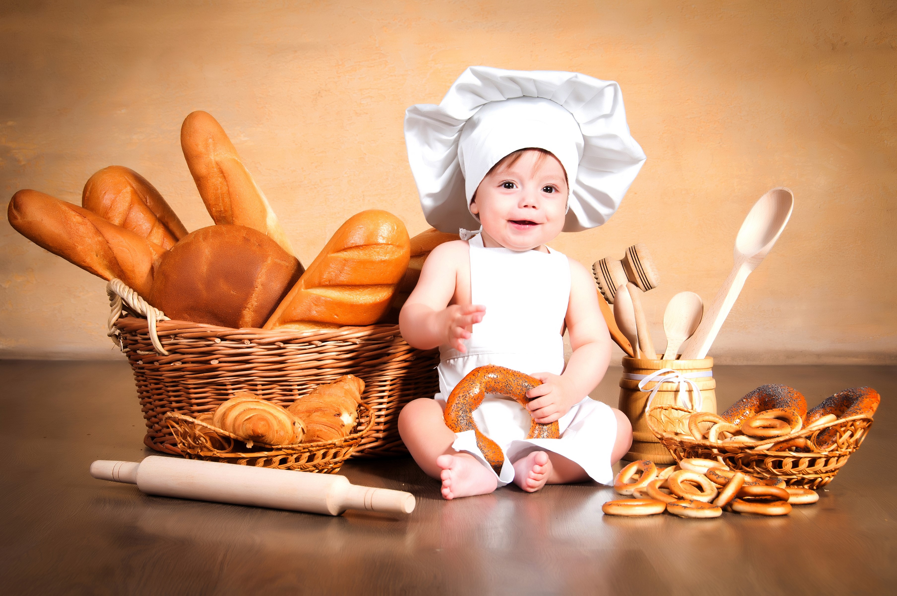 Baby in chef hat with bread and pastries HD Wallpaper