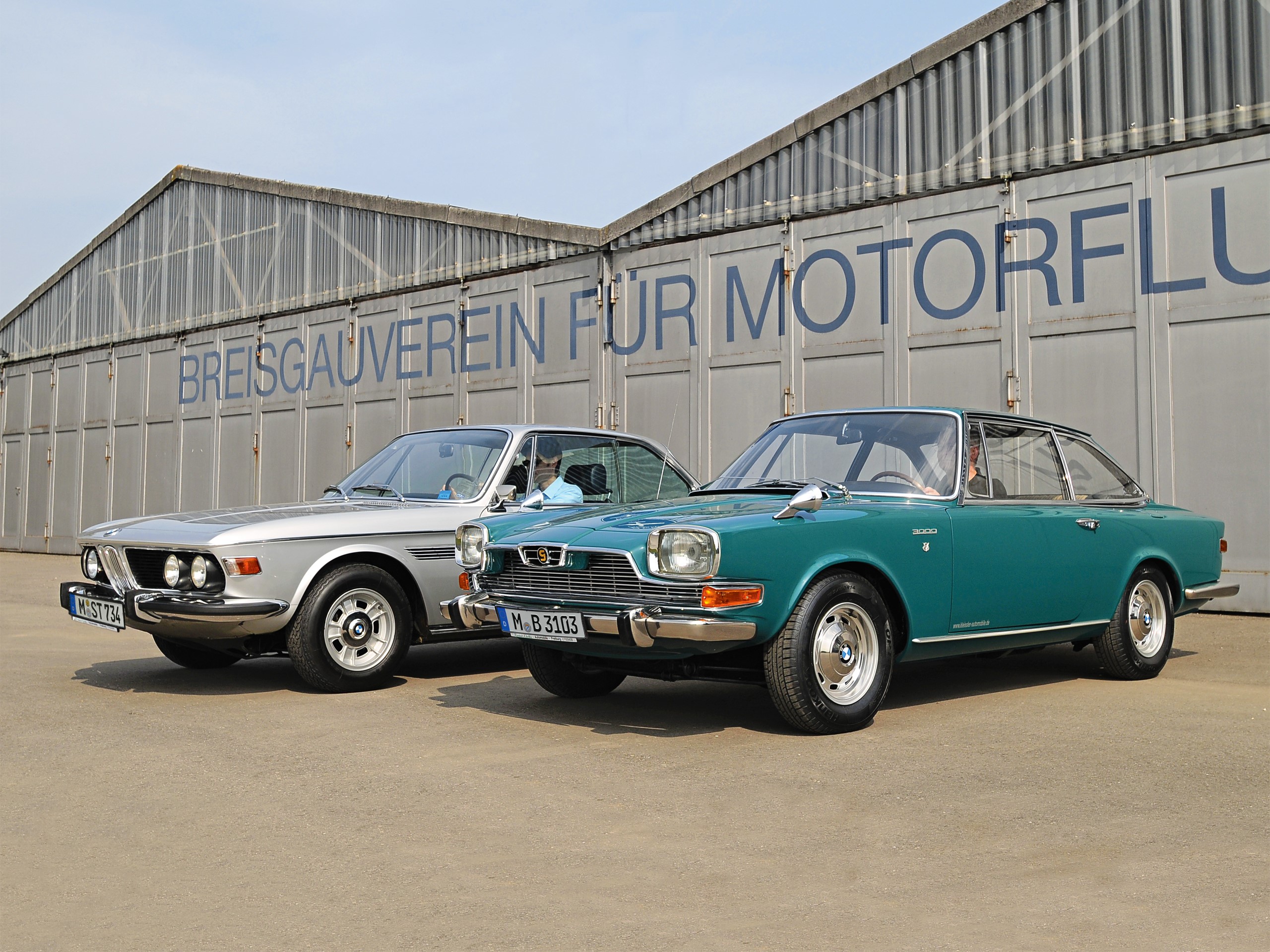 Two vintage BMW cars parked in front of a building HD Wallpaper