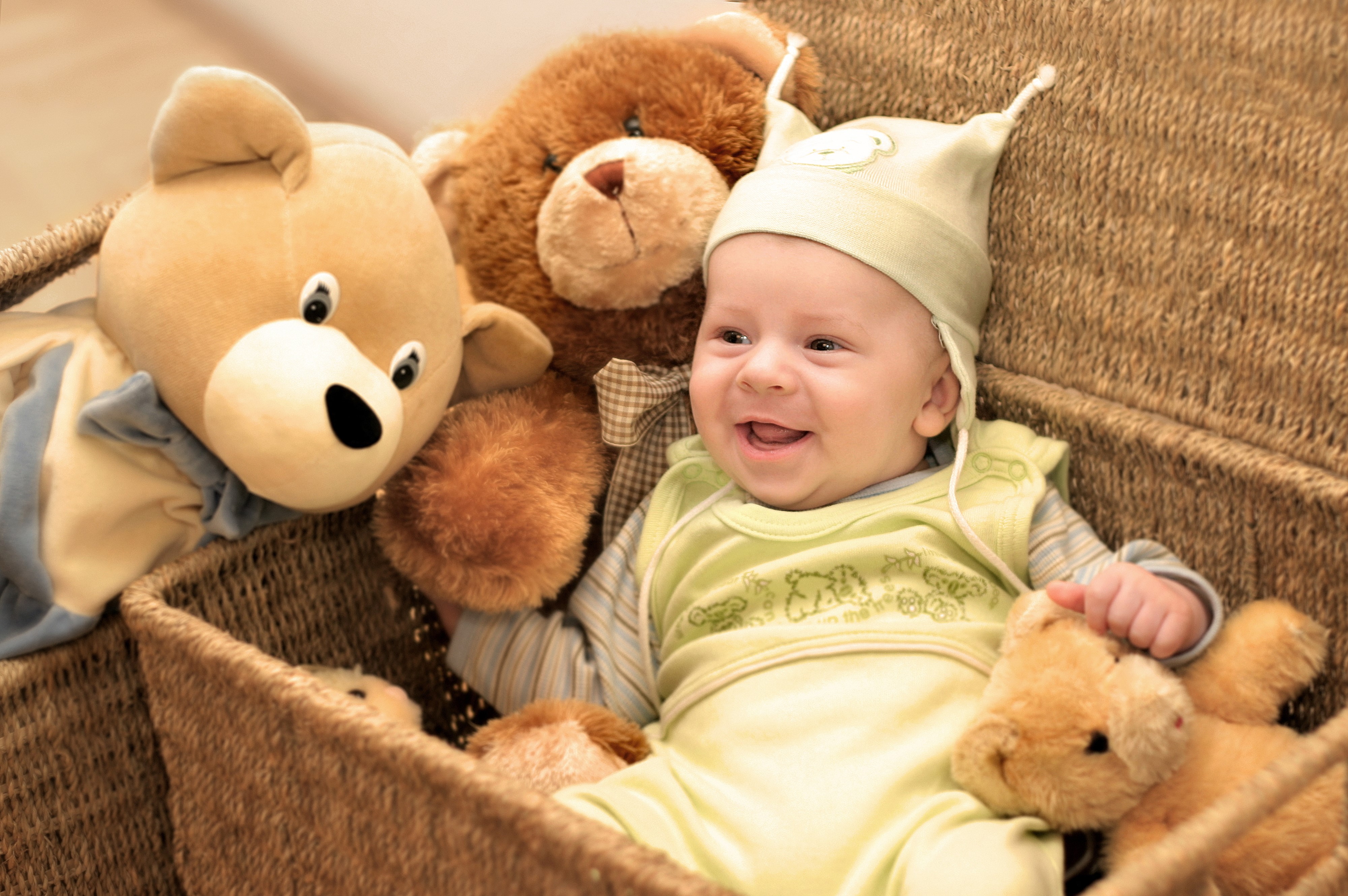 Baby smiling in a wicker basket with teddy bears HD Wallpaper