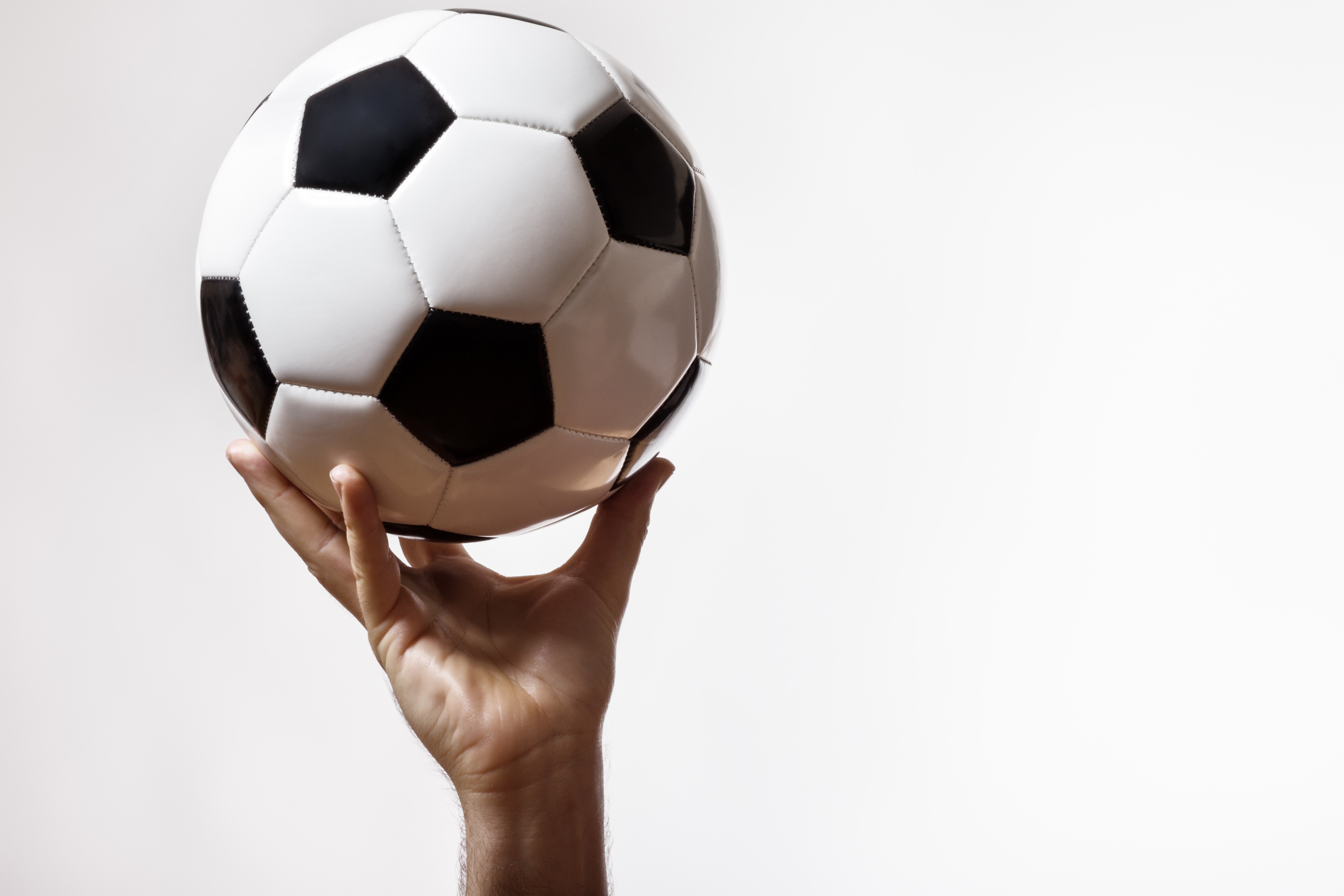 Soccer ball held by a hand HD Wallpaper
