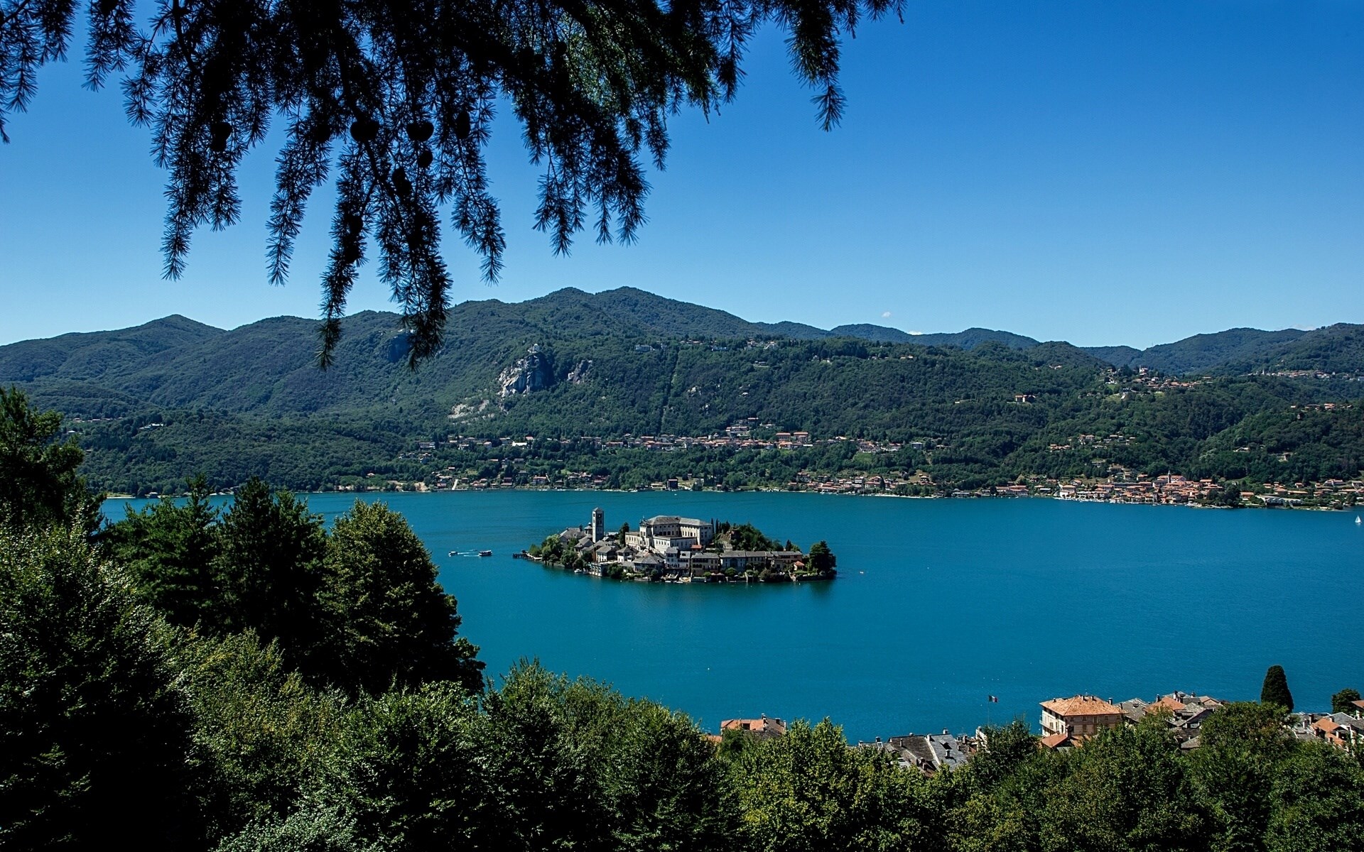 Island with buildings on a lake with mountains HD Wallpaper