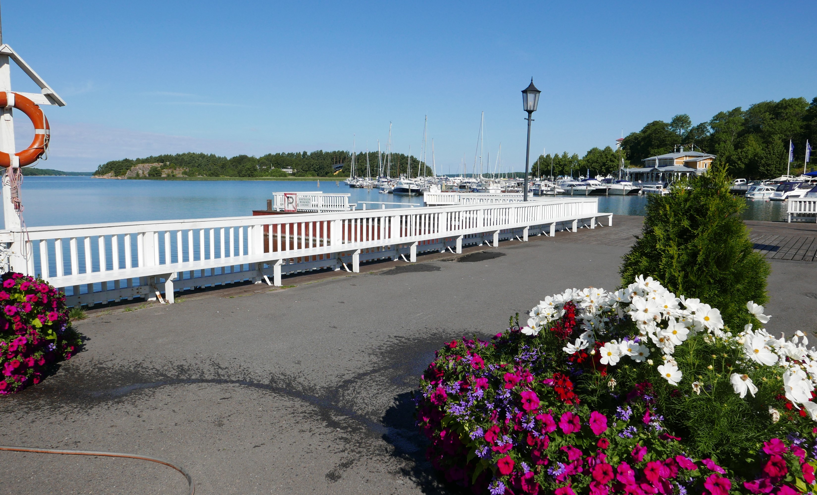 Marina with boats, flowers, and a white fence in Naantali, Finland HD Wallpaper