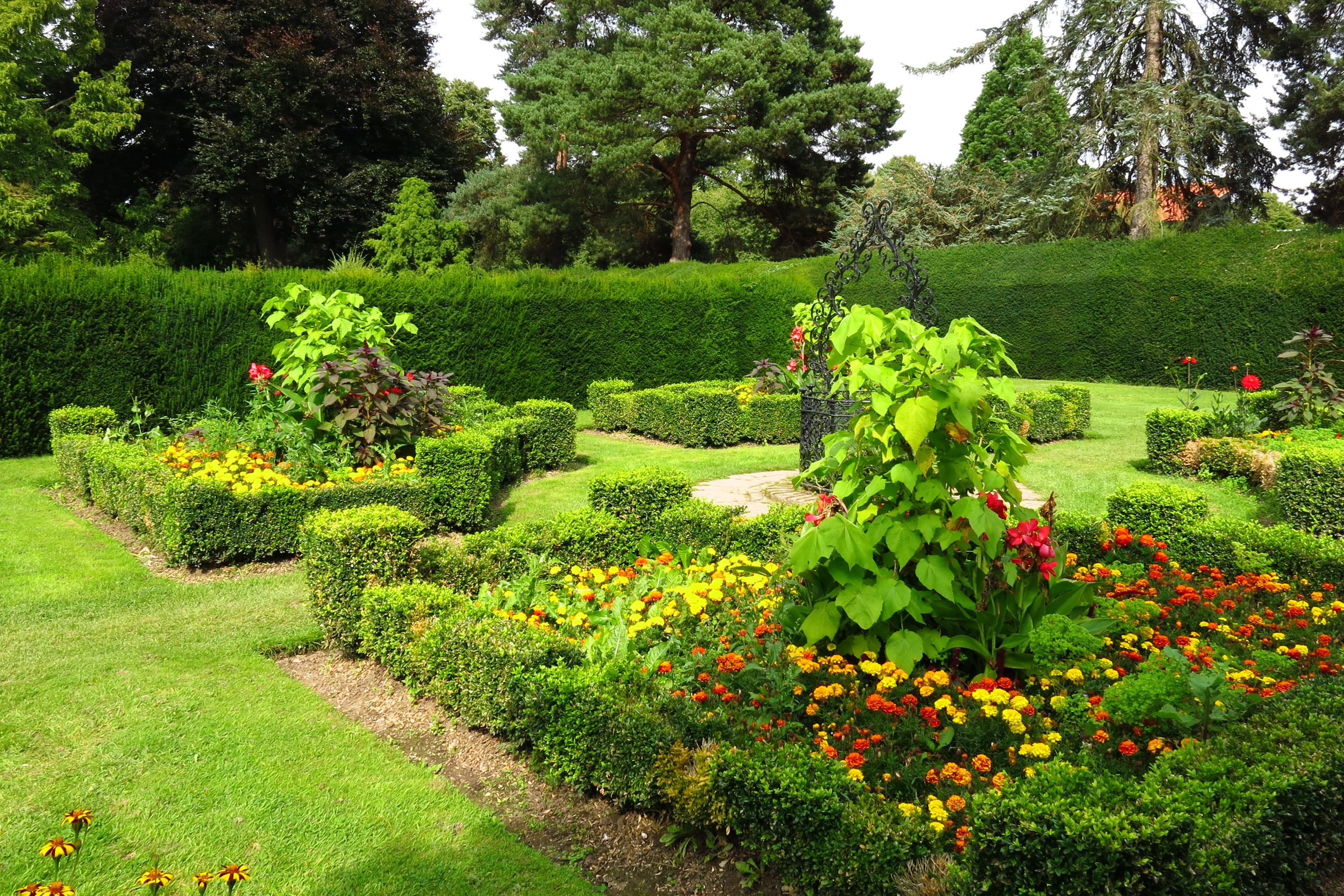 Formal garden with manicured hedges and colorful flowers HD Wallpaper