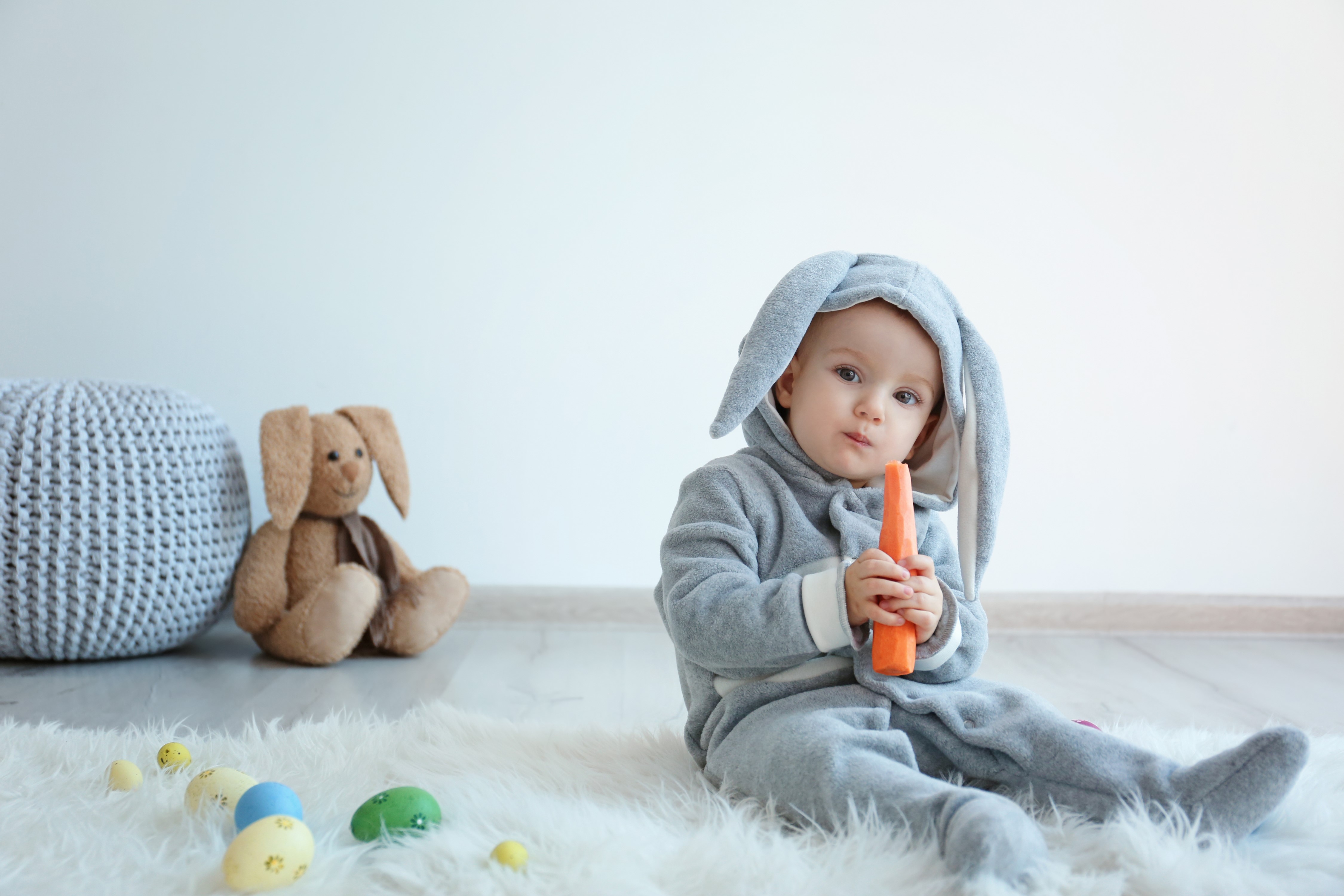Baby in bunny costume holding carrot with Easter eggs HD Wallpaper