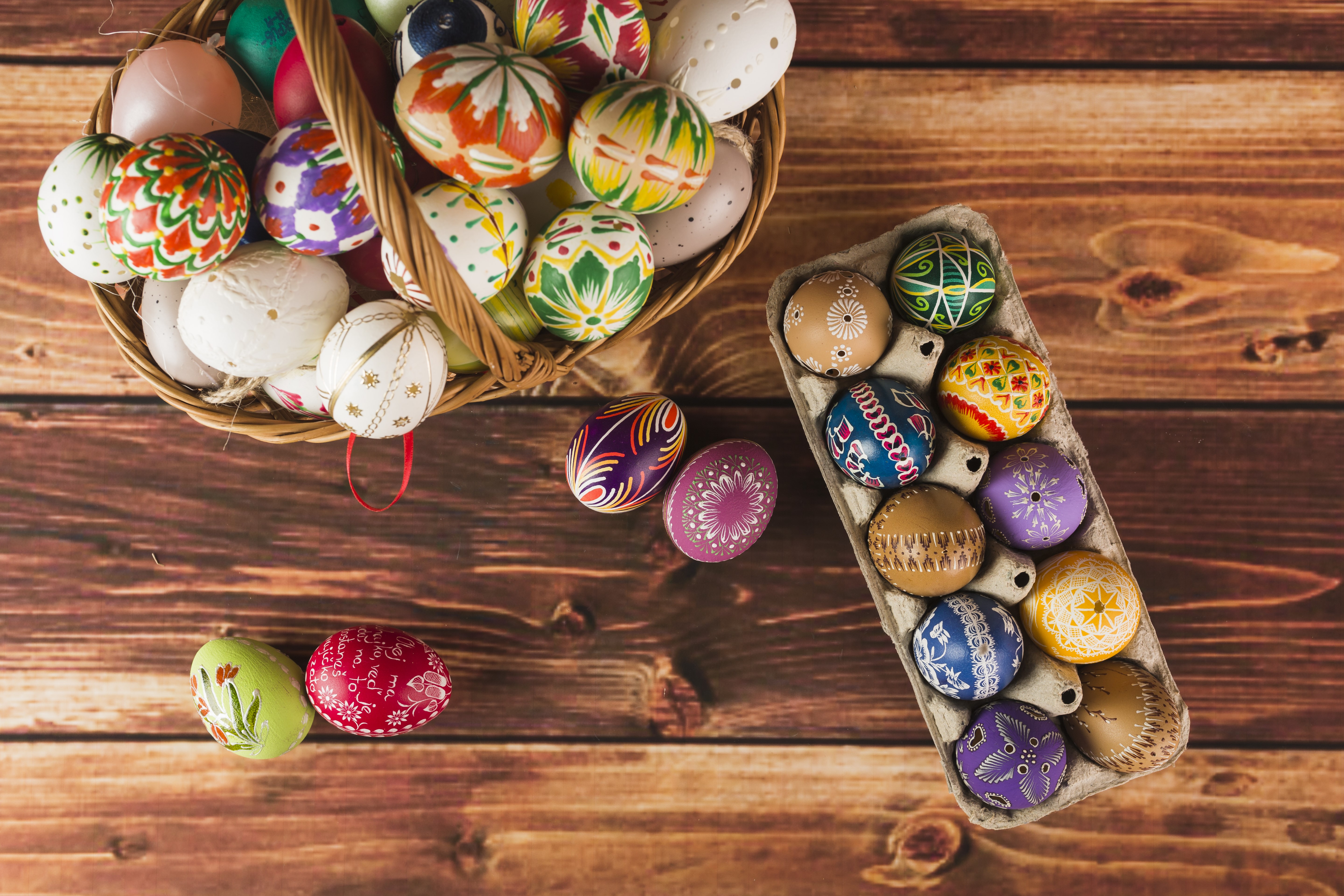Easter eggs in a basket and egg carton on wood HD Wallpaper