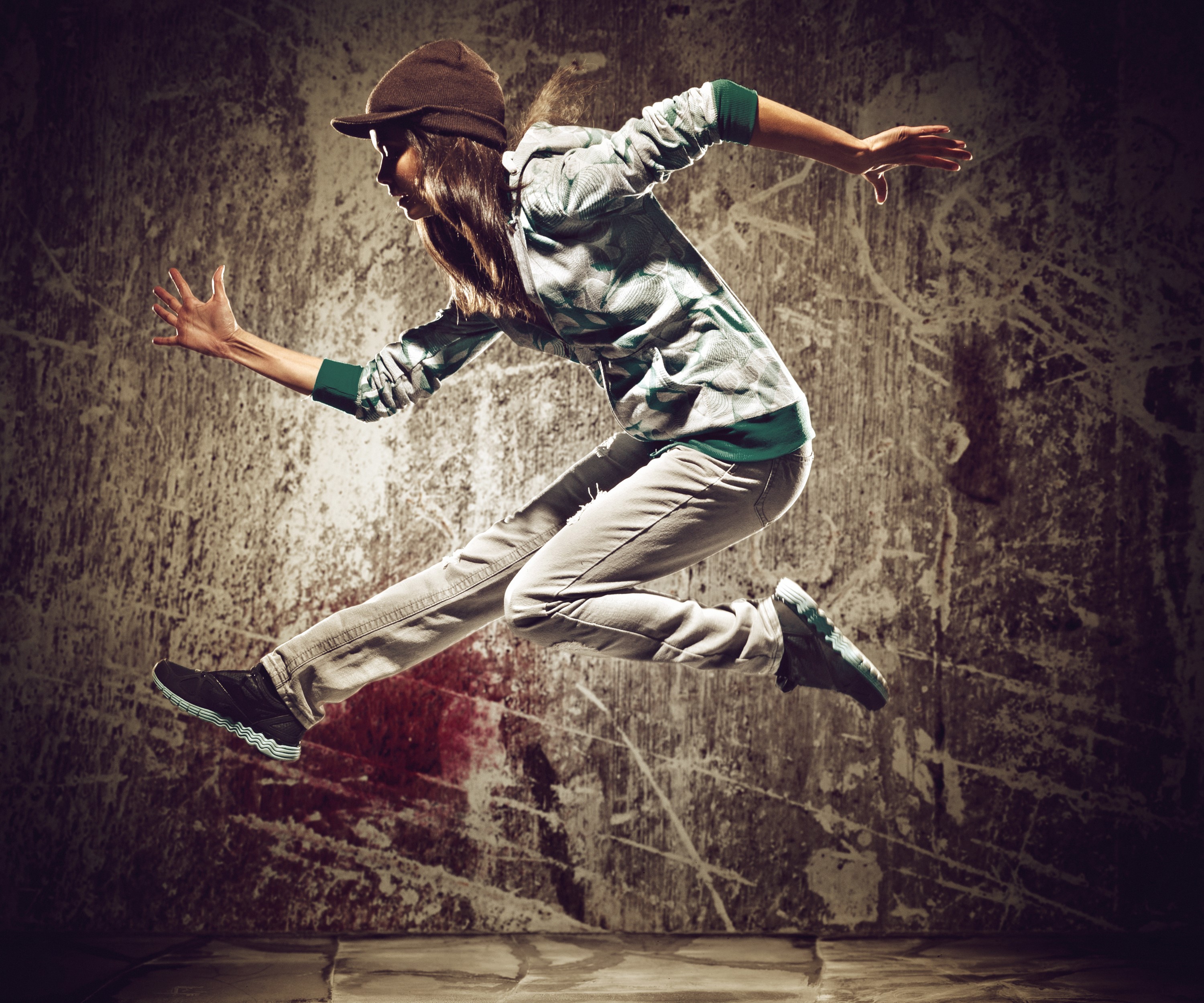 Young woman in a hoodie and hat jumping HD Wallpaper