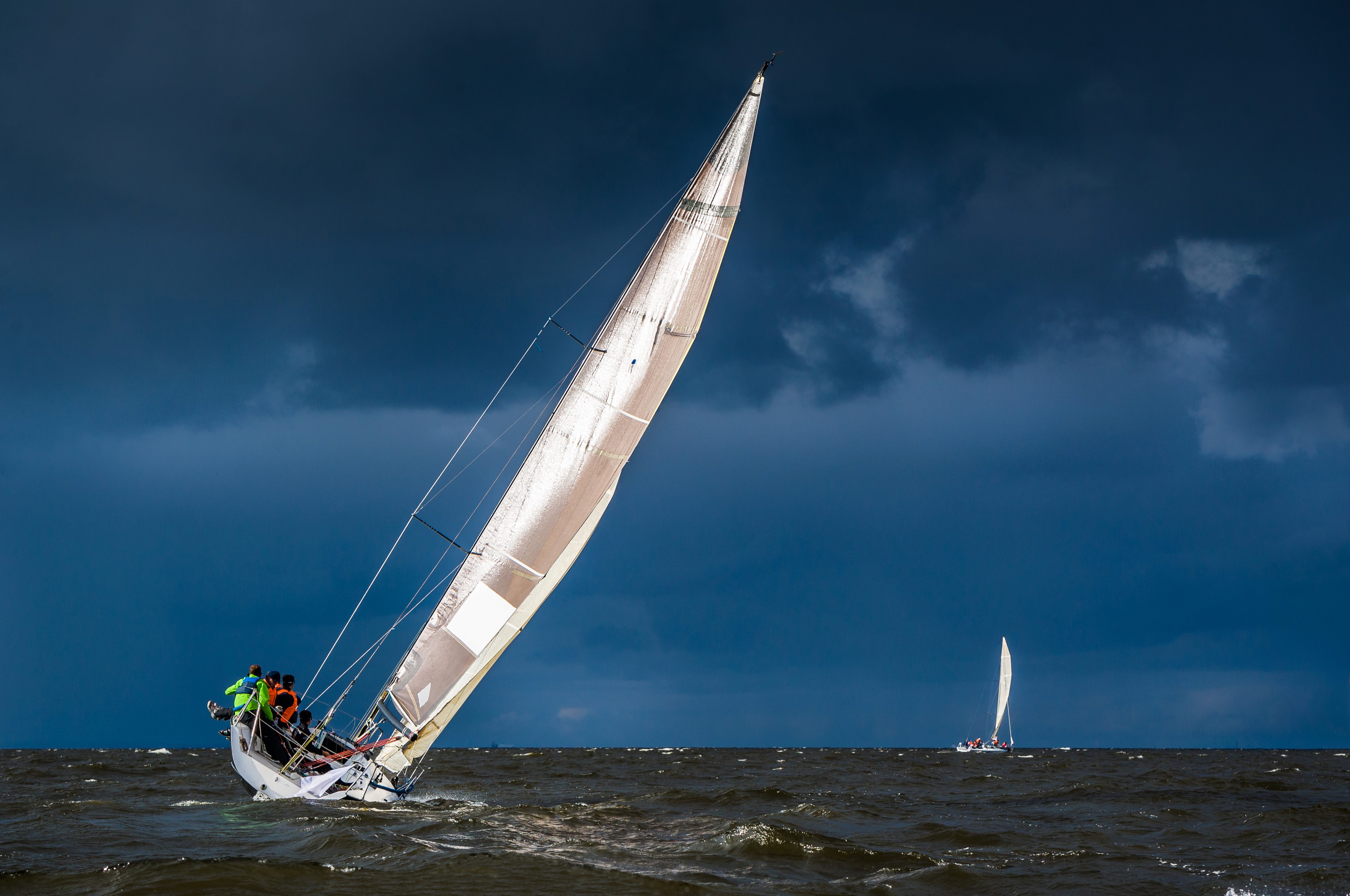 Sailboats racing on choppy water under stormy skies HD Wallpaper