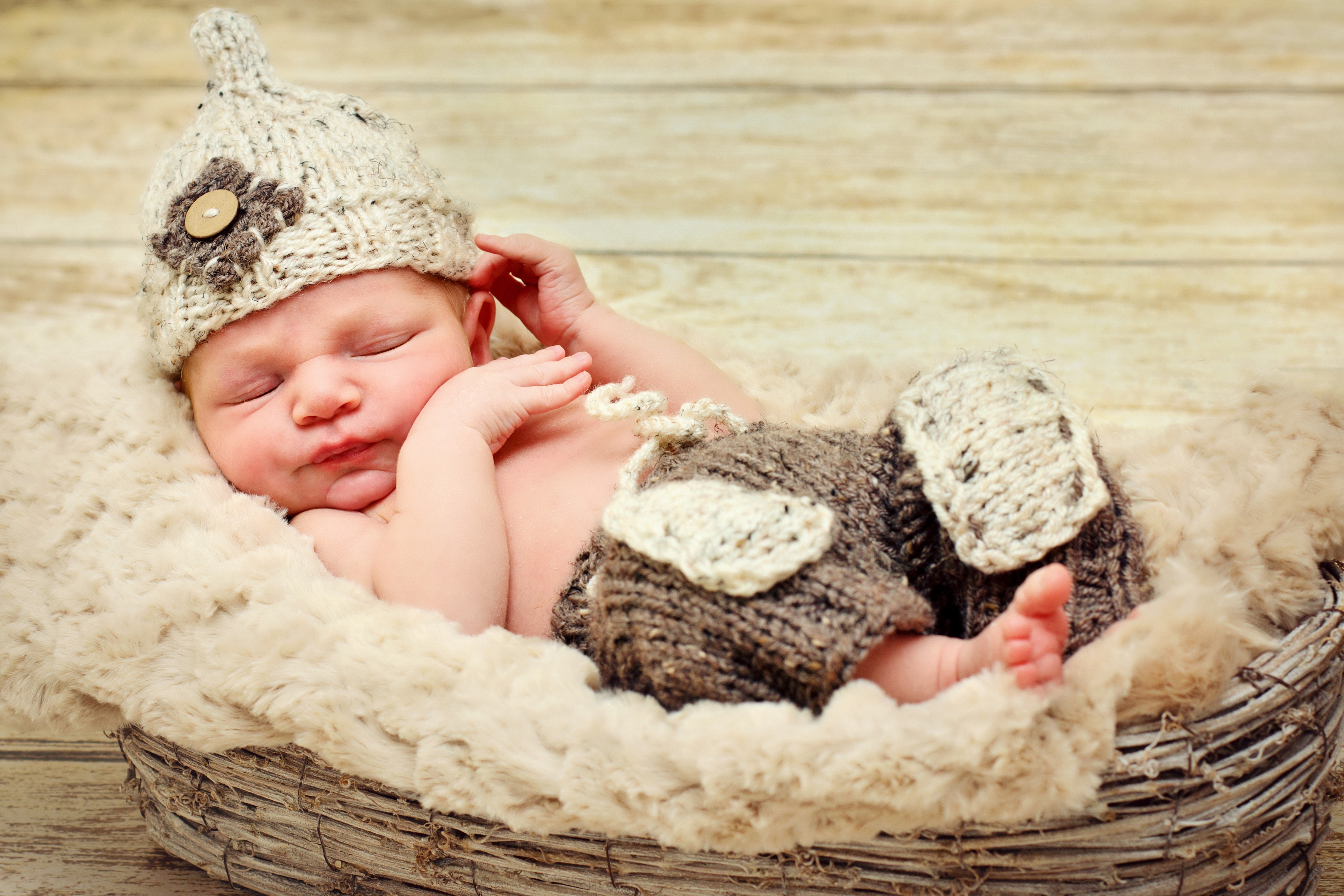 Newborn baby sleeping in a basket wearing a winter hat HD Wallpaper
