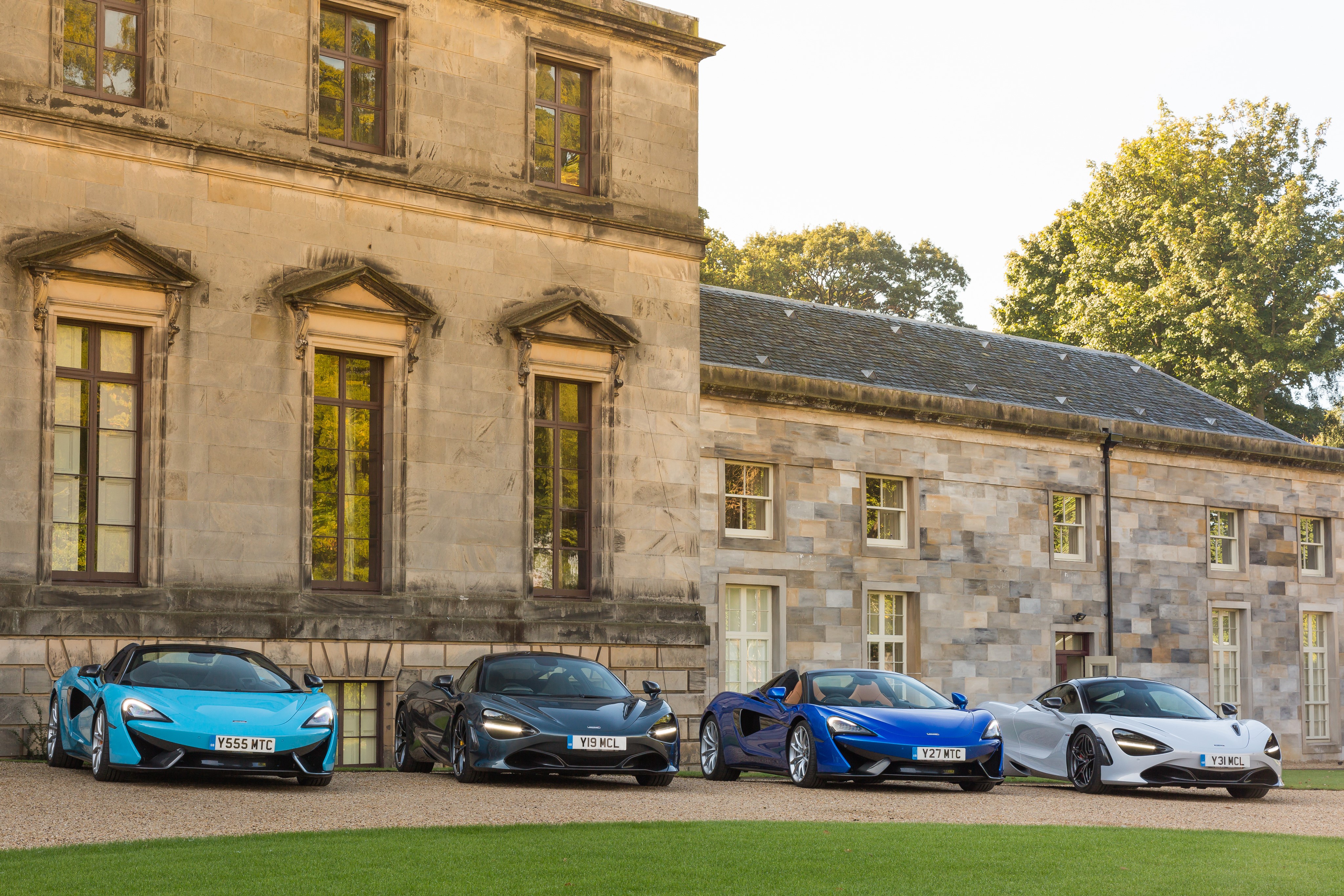 Four McLaren sports cars parked in front of a stone building HD Wallpaper