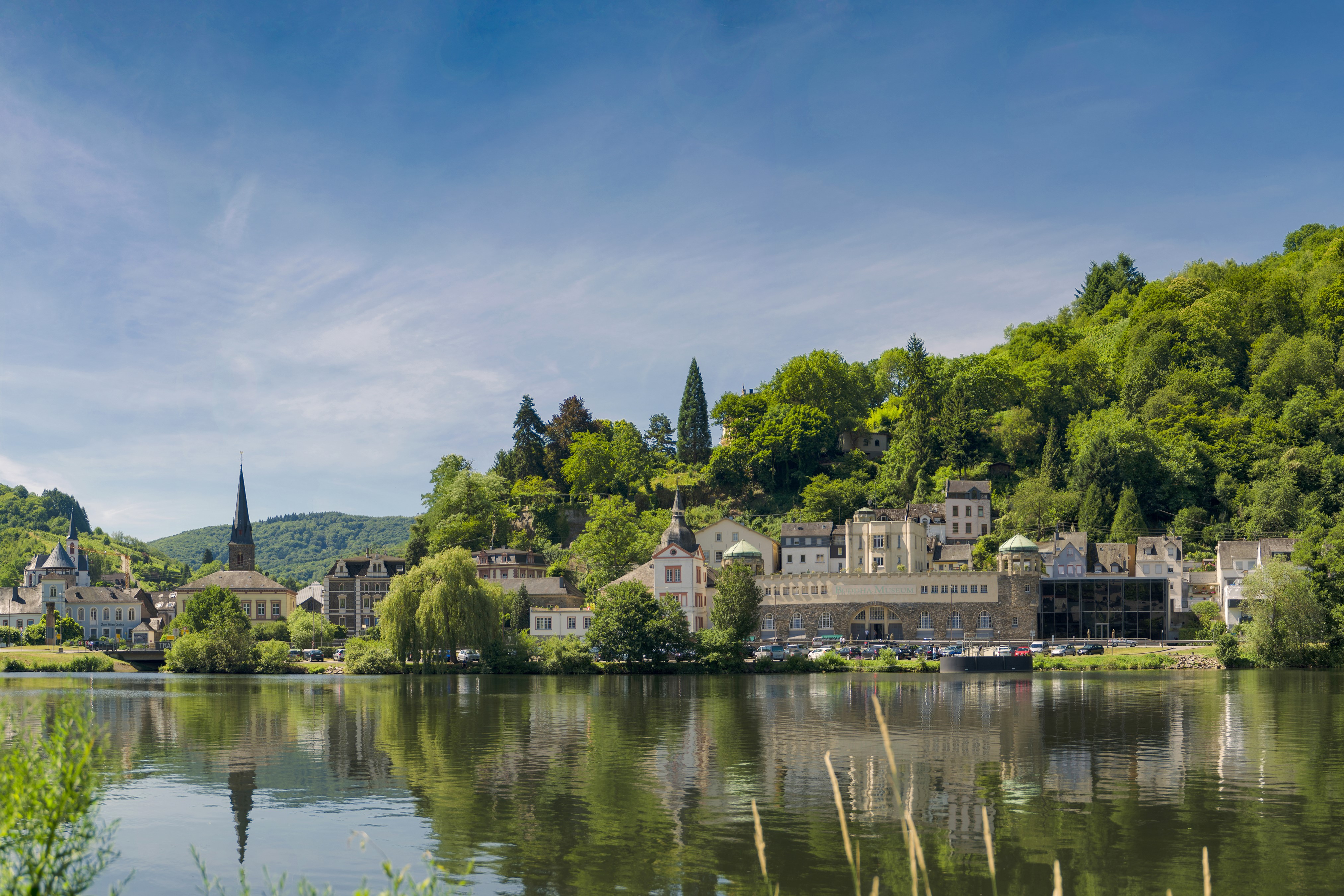Riverfront town with church spire and green hills HD Wallpaper